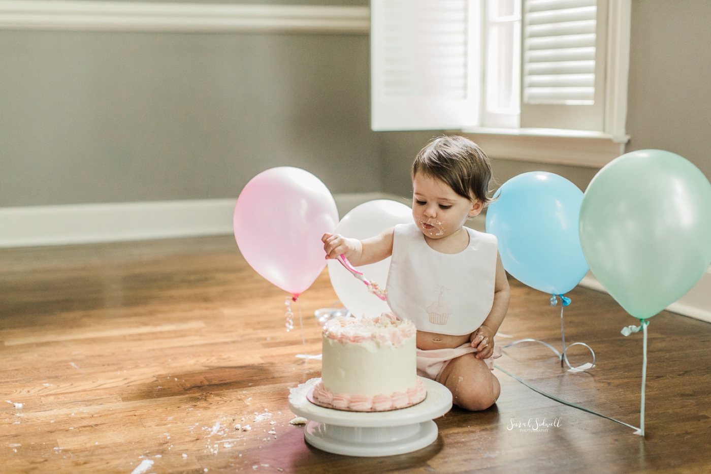A baby girl smashes her first birthday cake. 