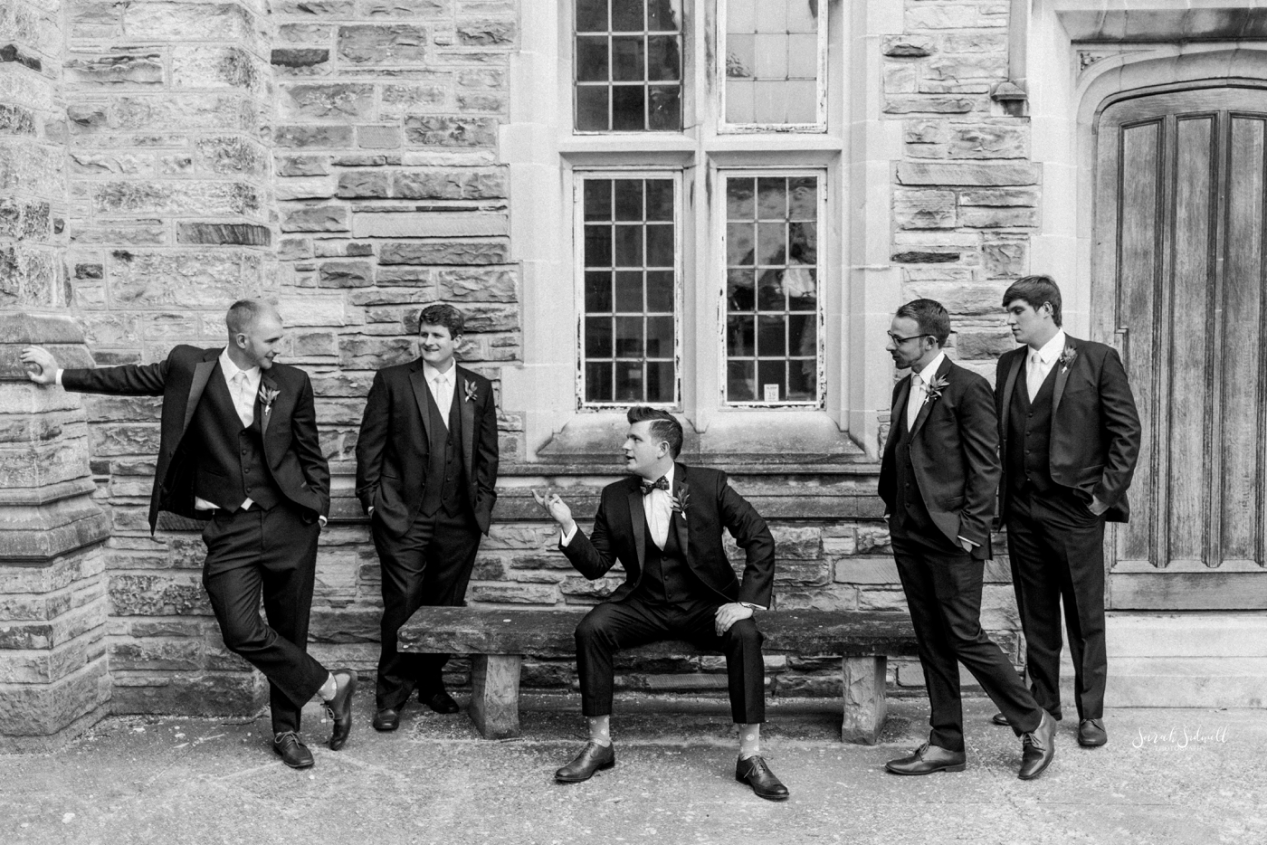 A groom casually chats with his groomsmen. 