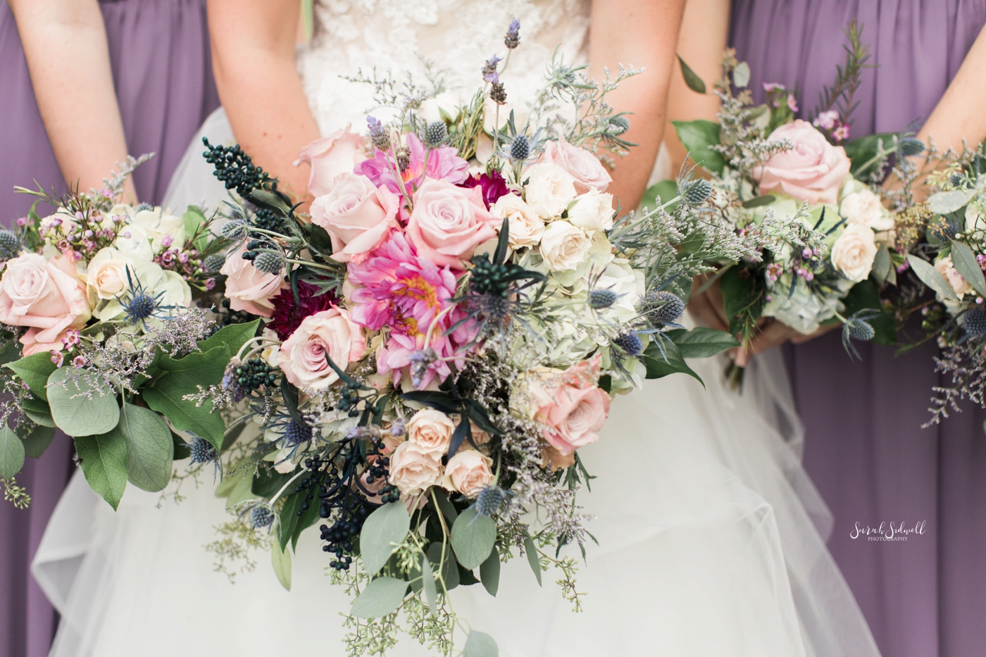 A bridal party hold their bouquets together. 