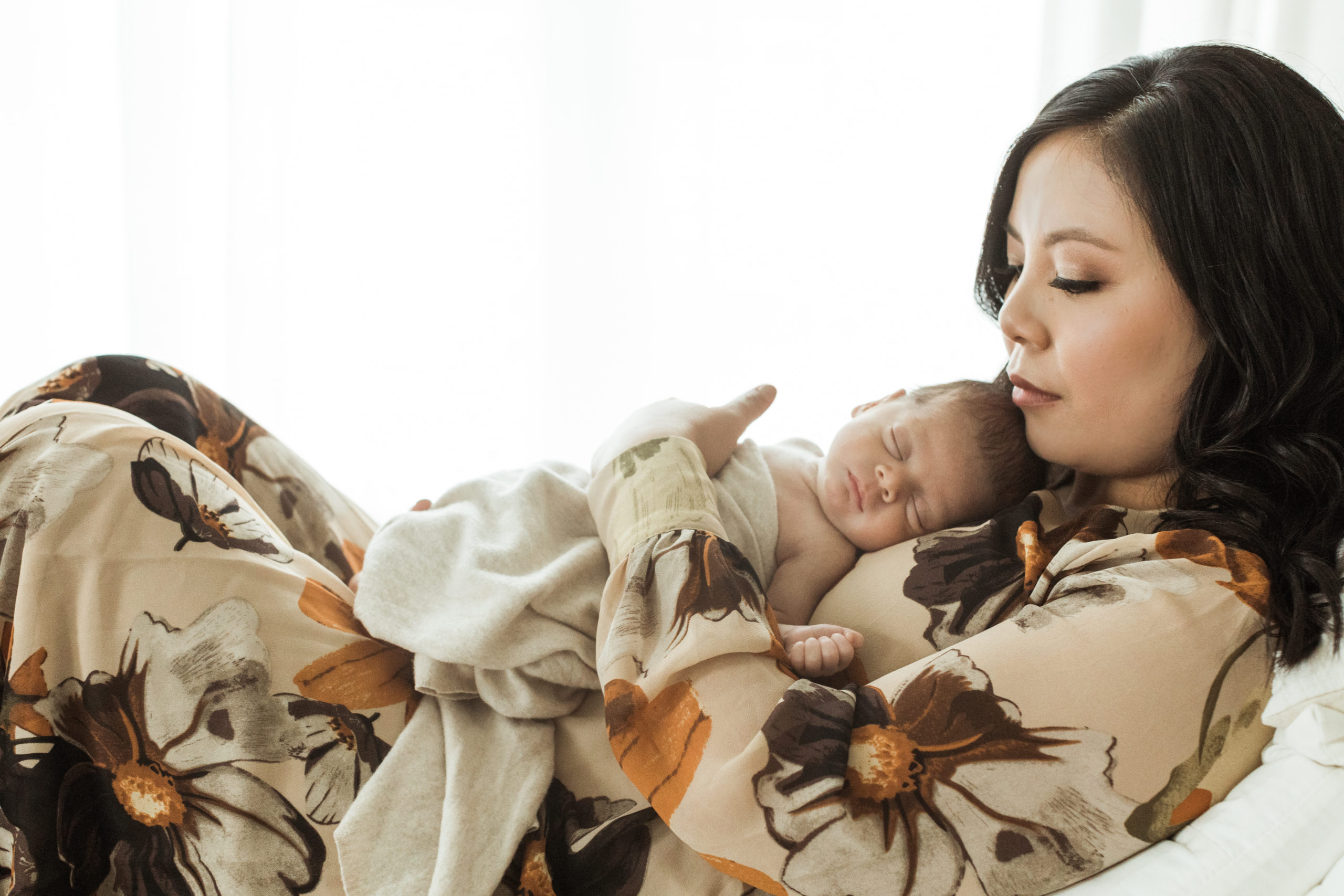 Photo of mama laying down with her newborn baby boy on her chest. Both mama and baby boy with eyes closed. Mama's makeup done by professional hair and makeup artist.