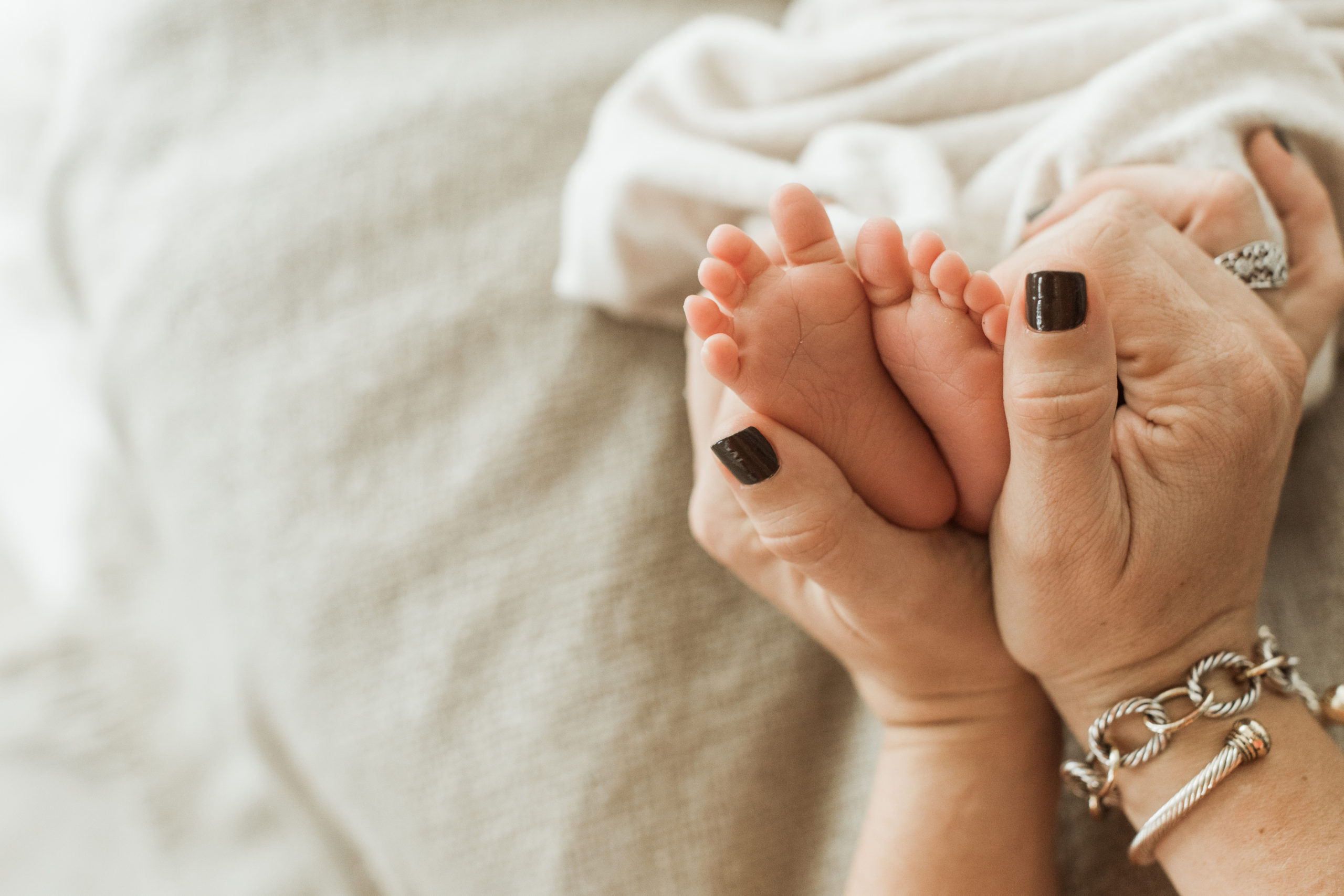 Photo of newborn baby boy's feet being held by mama's hands.