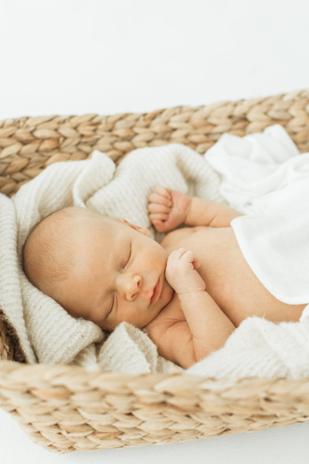 Newborn baby boy in woven basket sleeping. 