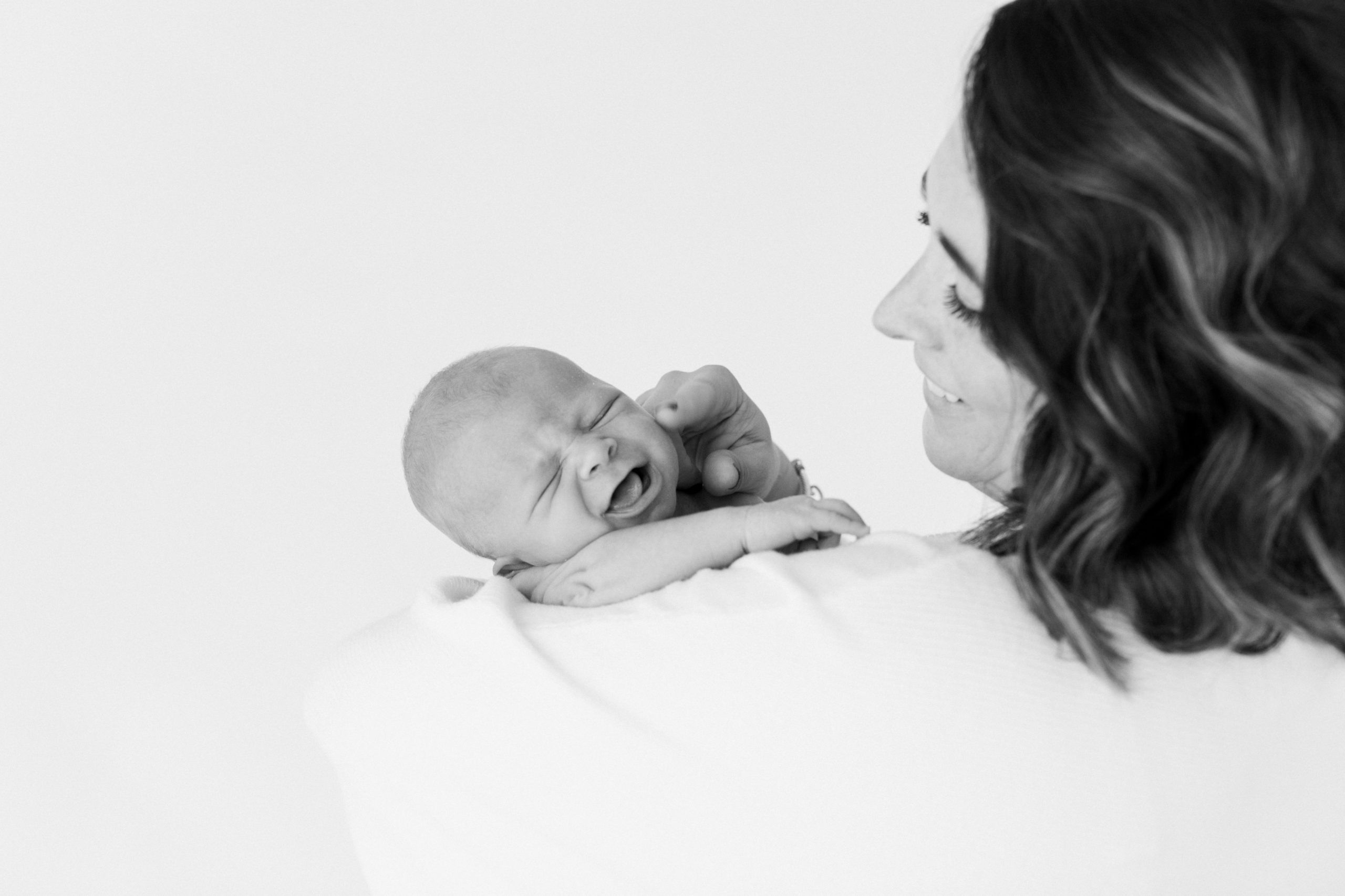 Black and white photo of mama and smiling newborn baby boy.