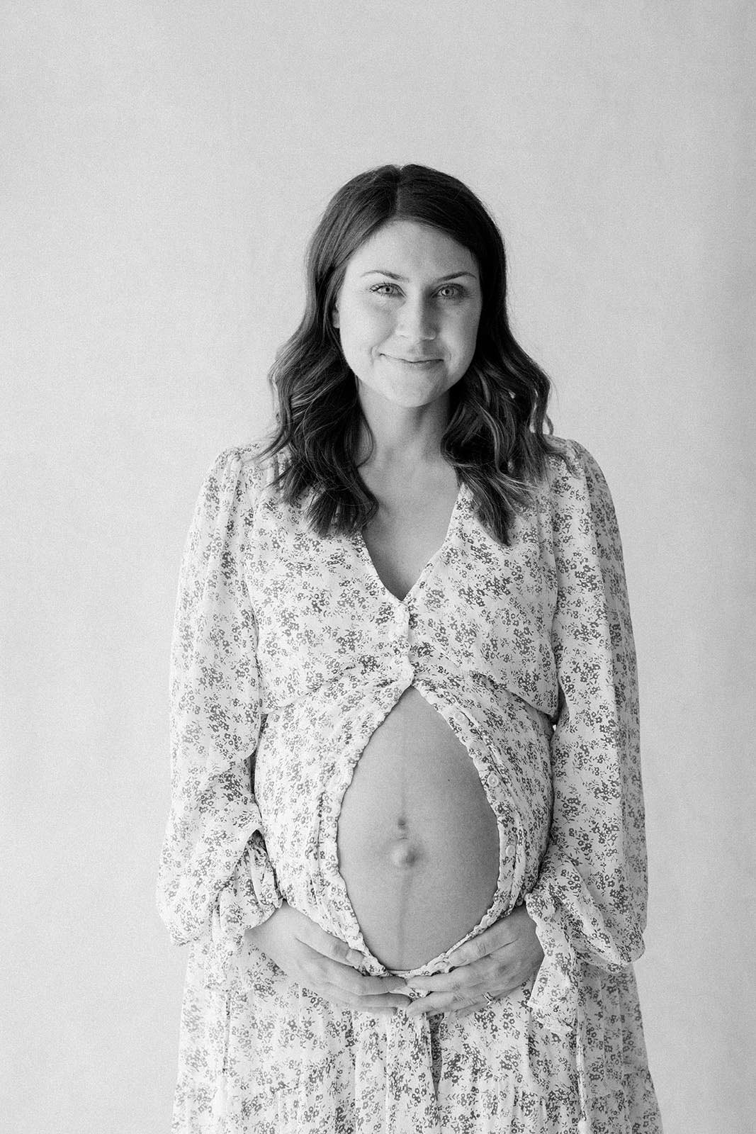 black and white photo of expecting mama looking and smiling at camera.