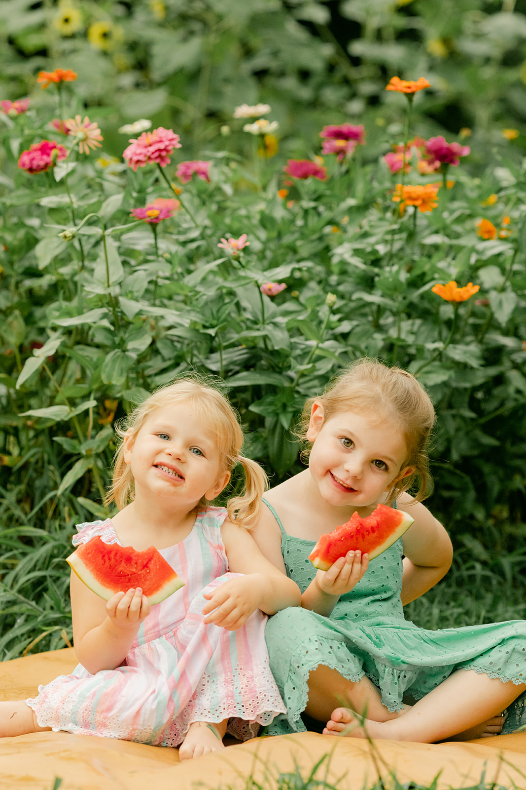 outdoor motherhood minis in garden. photographed in nashville photographer. two sisters eating watermelon