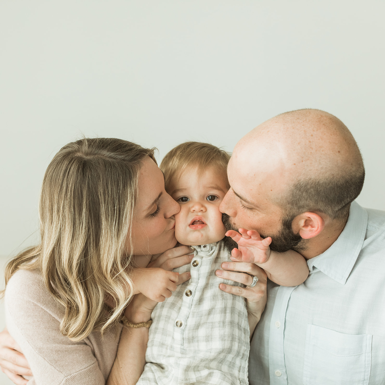 braden's 1st birthday photoshoot in nashville studio. parents kissing their baby boy