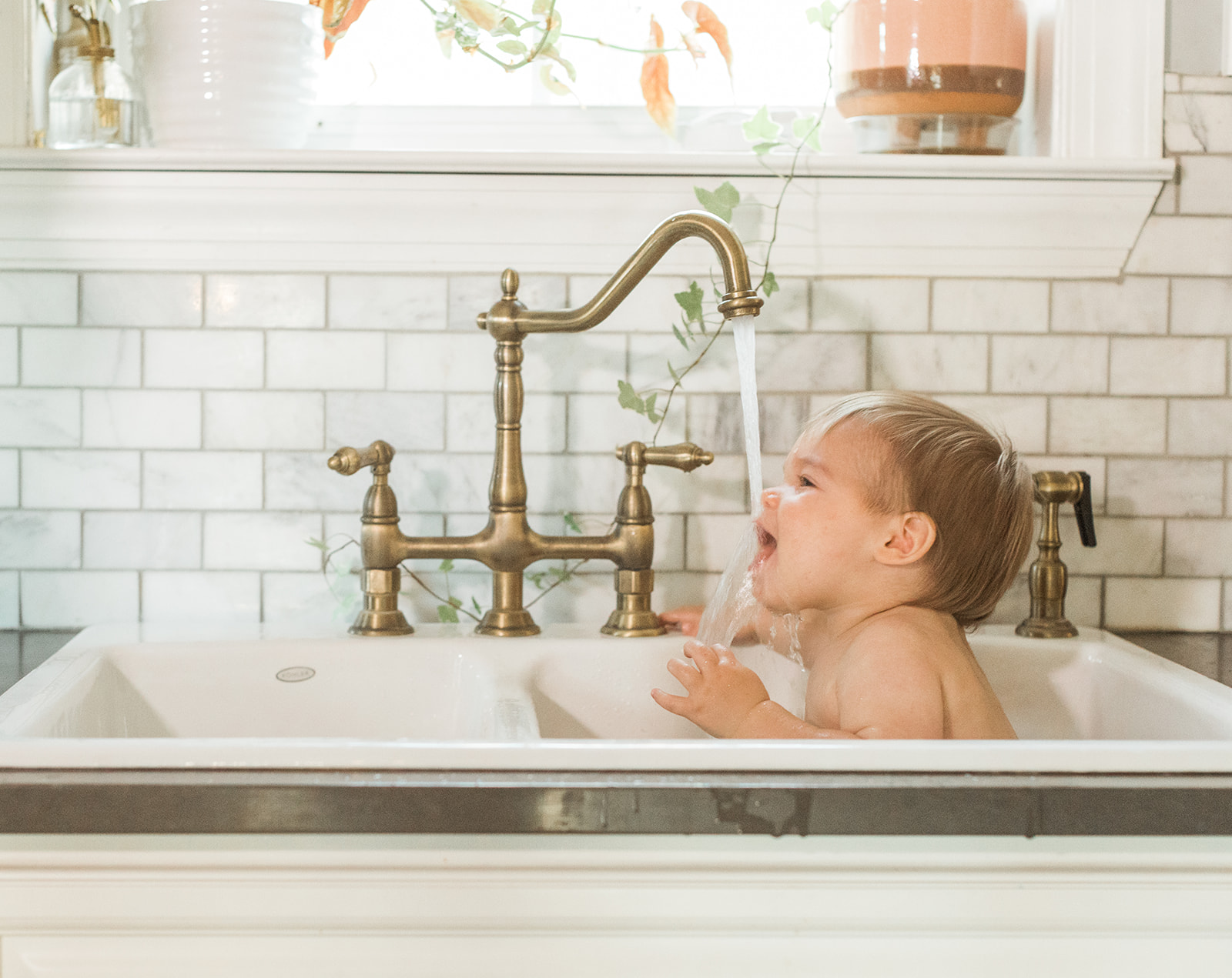 braden's 1st birthday photoshoot in nashville studio. baby taking a bath in kitchen sink