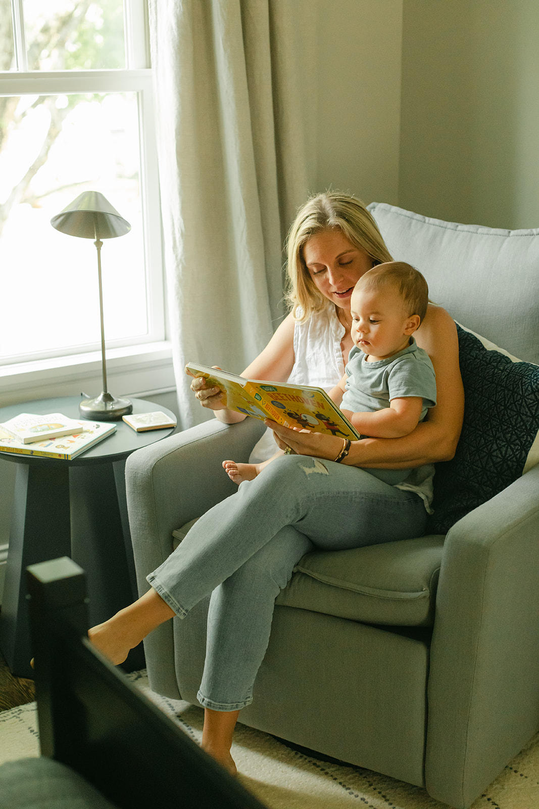 1 year milestone session for baby boy. Cozy at home session. Mama reading a book to baby boy