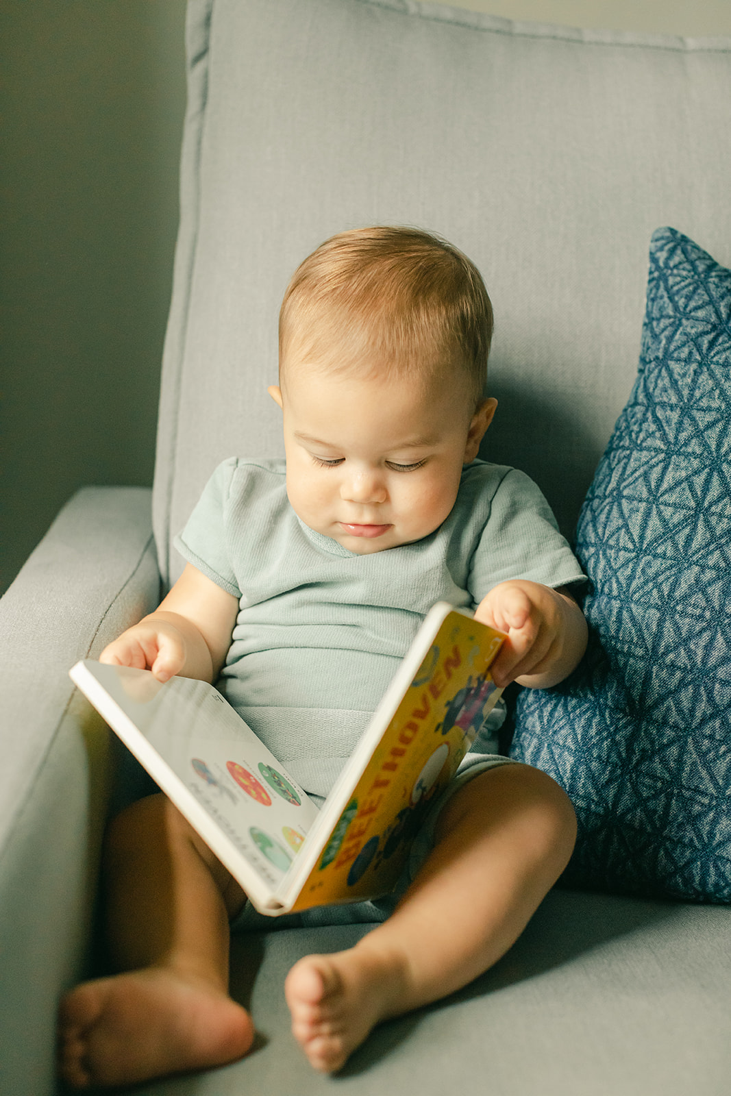 1 year milestone session for baby boy. Cozy at home session. baby boy with book