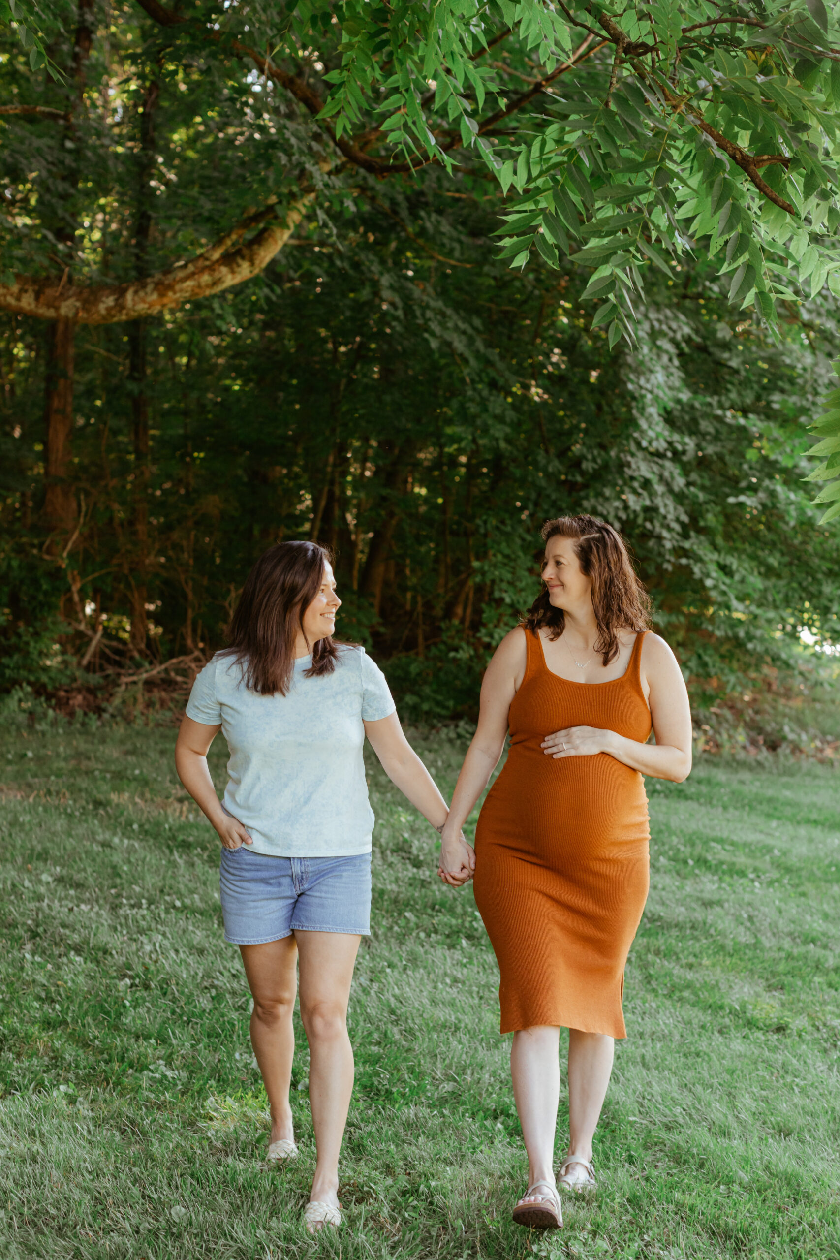 LGBTQ moms holding hands walking. Maternity session & backyard summer family session in Nashville, TN