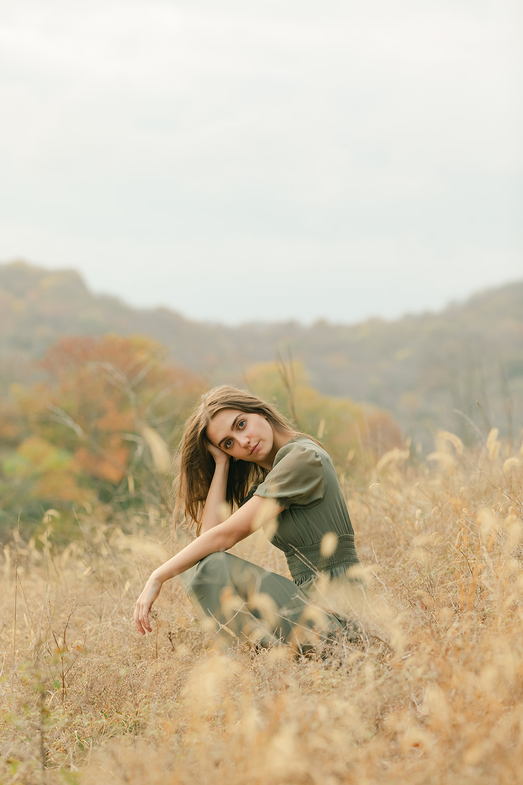 teenage girl during fall senior photos in open field.