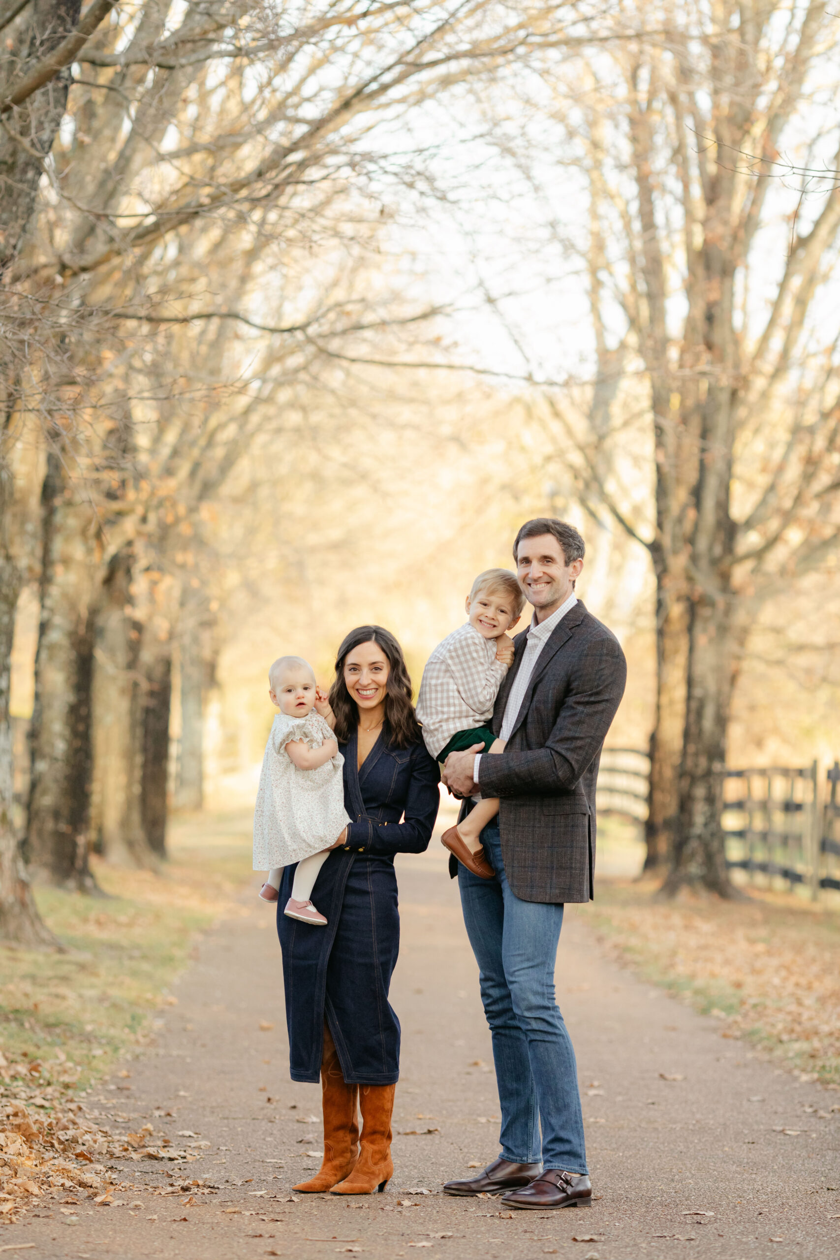 fall family photos in tree filled path. parents with little girl and boy