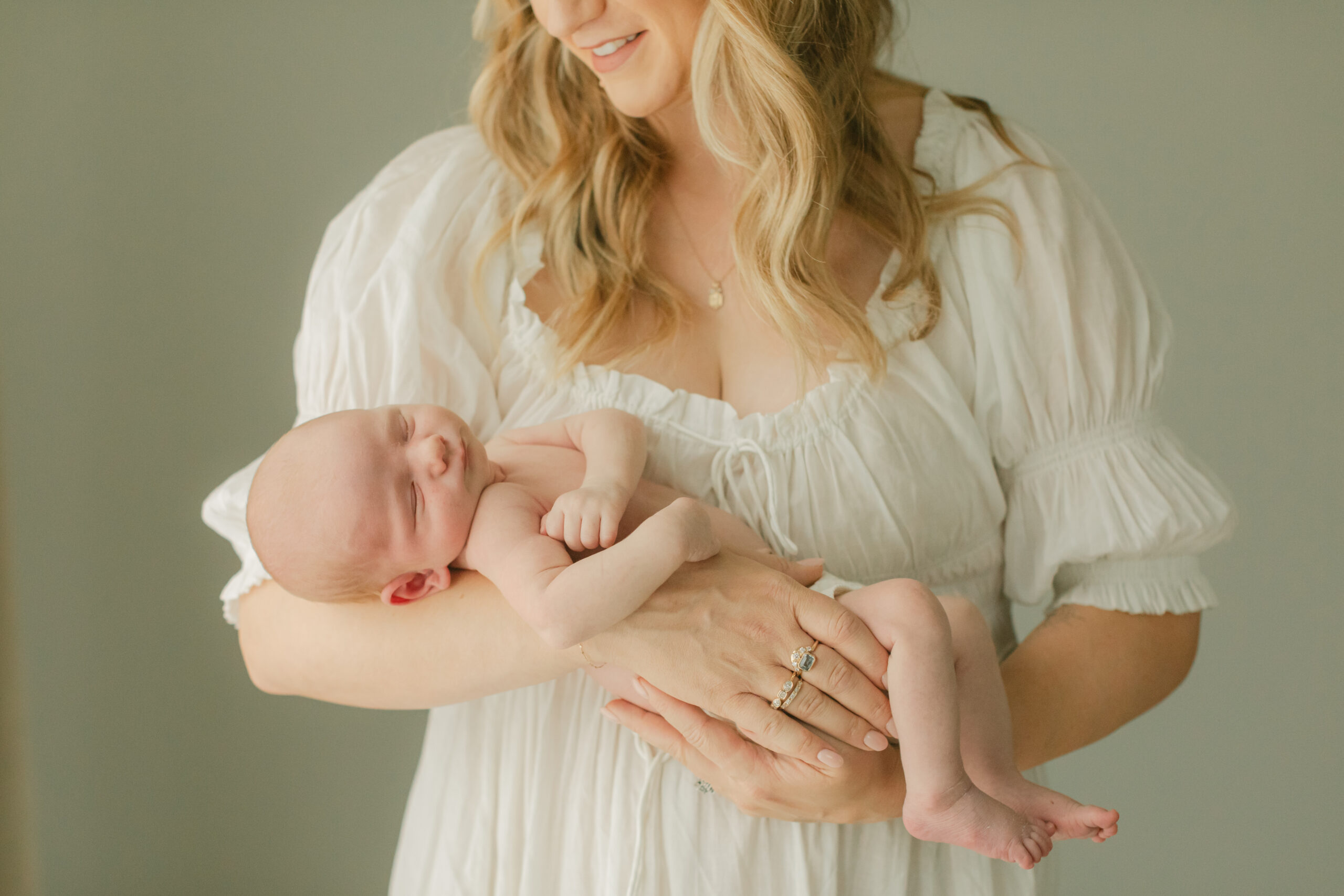 newborn baby being held by mama in white dress