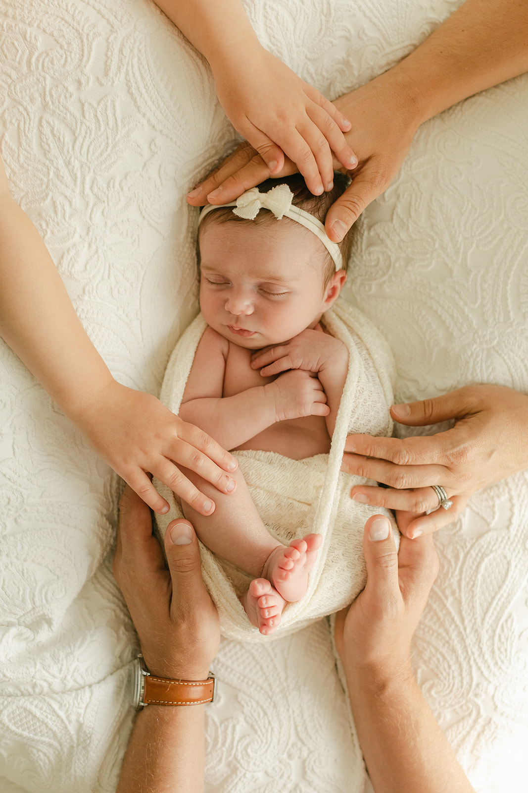 sleepy newborn baby girl in cream color swaddle