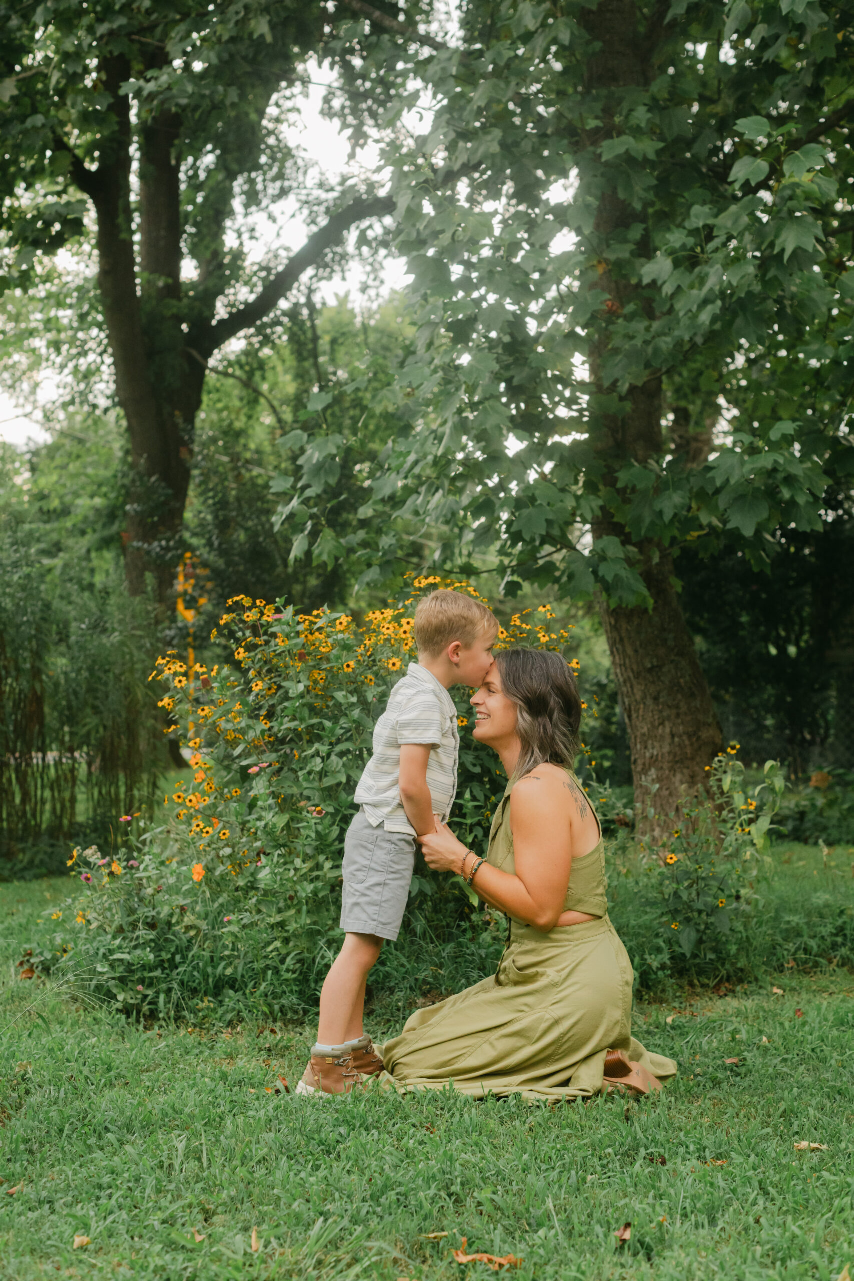 mama with her toddler boy in the garden during motherhood minis. boy giving mom a kiss on the forehead