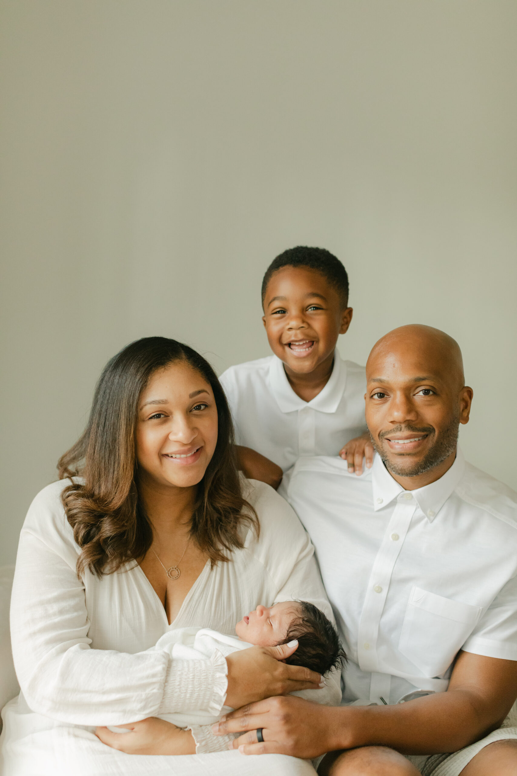 family in white coordinating outfits for newborn photo session