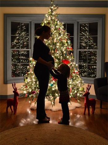 pregnant woman with daughter in front of christmas tree