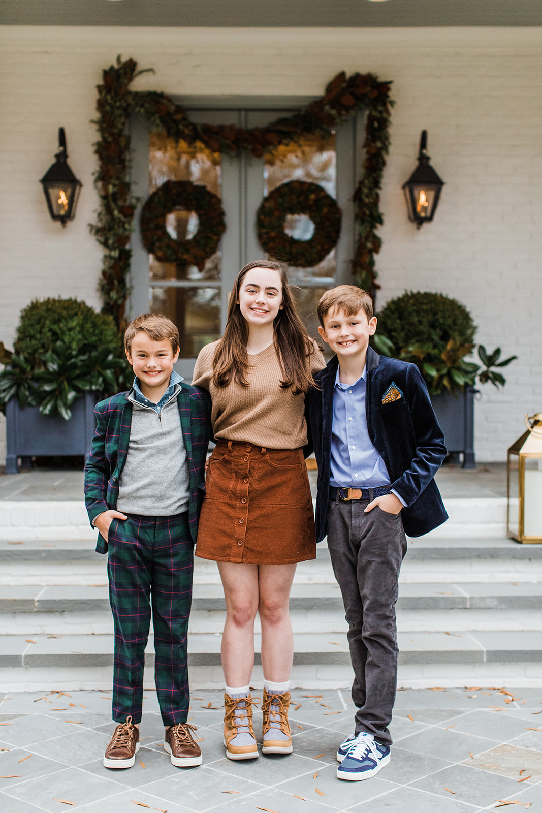 three siblings (eldest sister and two younger brothers). christmas family photos in front of home