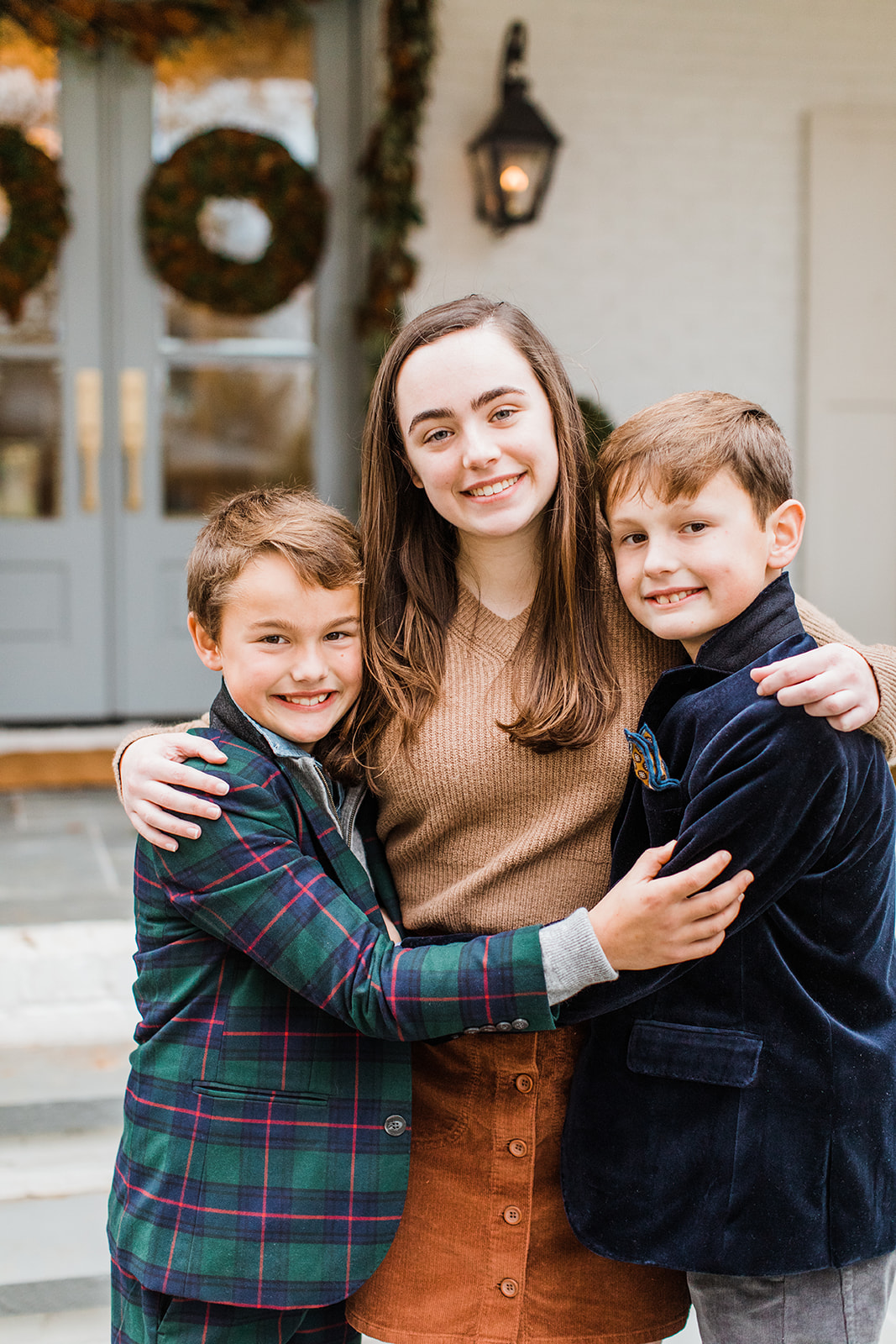 three siblings (eldest sister and two younger brothers). christmas family photos in front of home