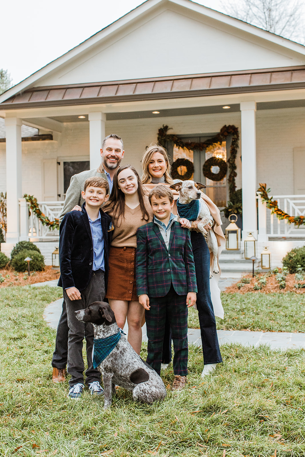 family photo (mom, dad, eldest daughter and two young boys with two family dogs). christmas family photos in front of home