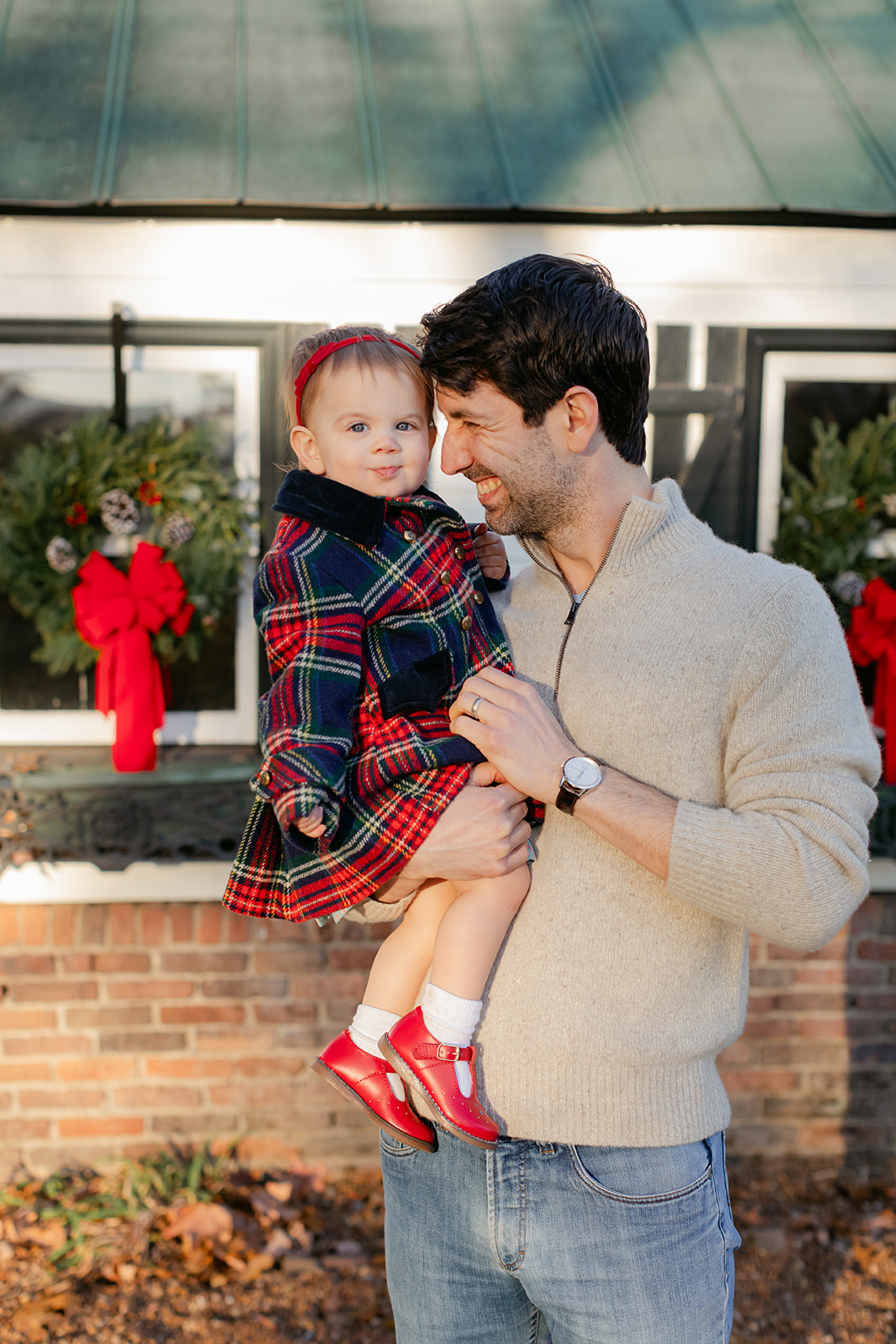 dad and baby girl in christmas coat. christmas family photos in front of home