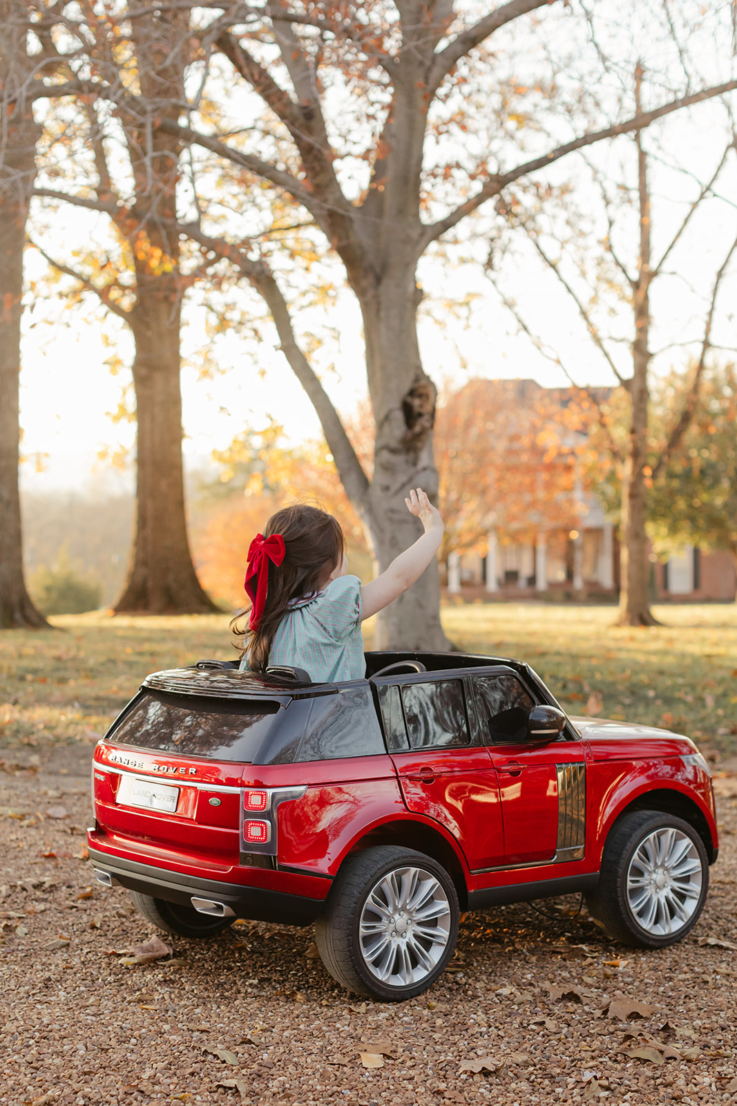 little girl in red toy car. christmas family photos in front of home