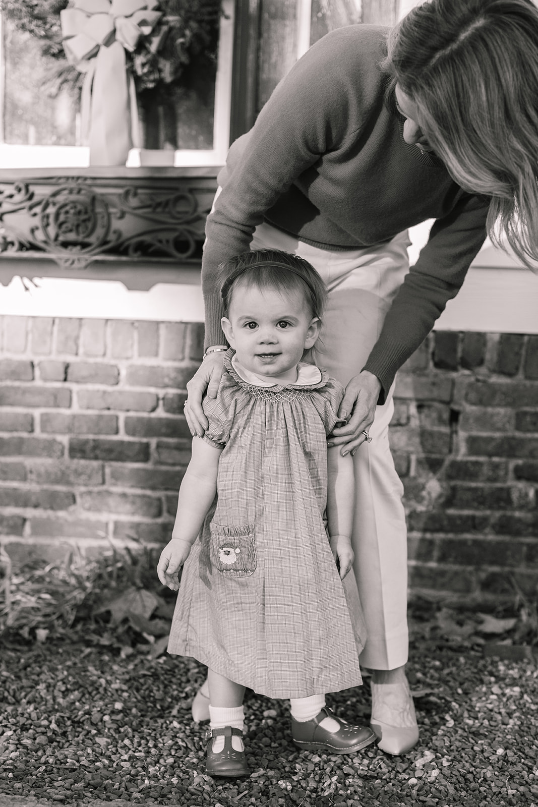 mom with baby girl. christmas family photos in front of home