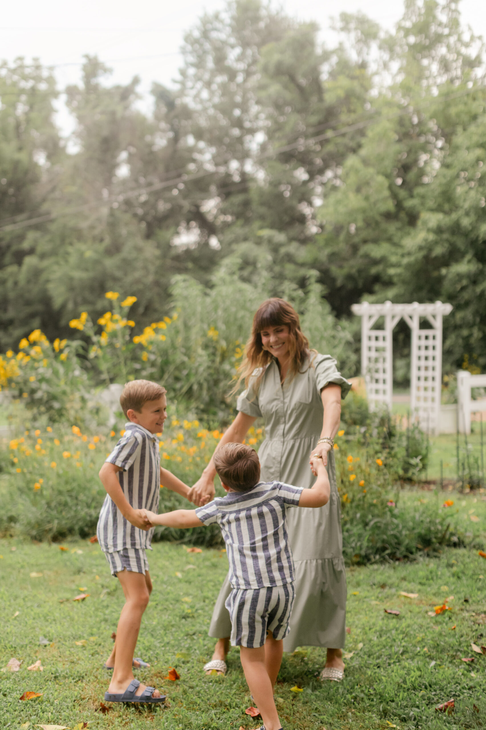 mama and her two boys holdings hands going in a circle in flower garden. motherhood minis photo session in nashville