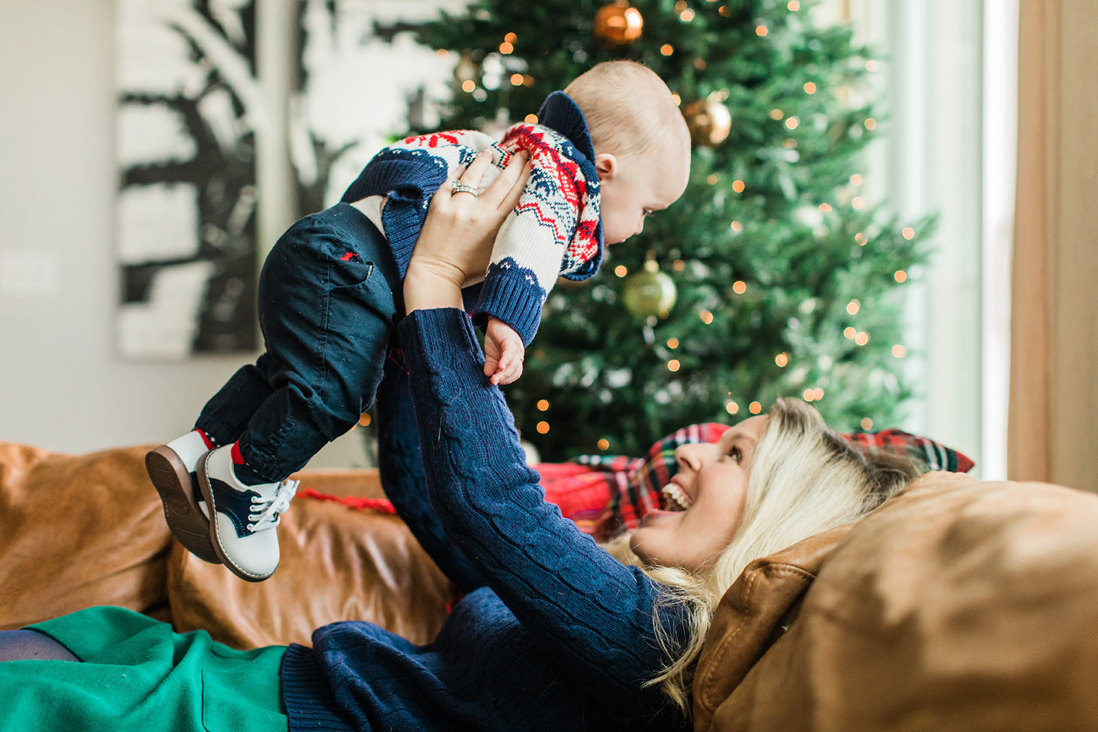 mom and baby boy on couch. christmas family photos in living room