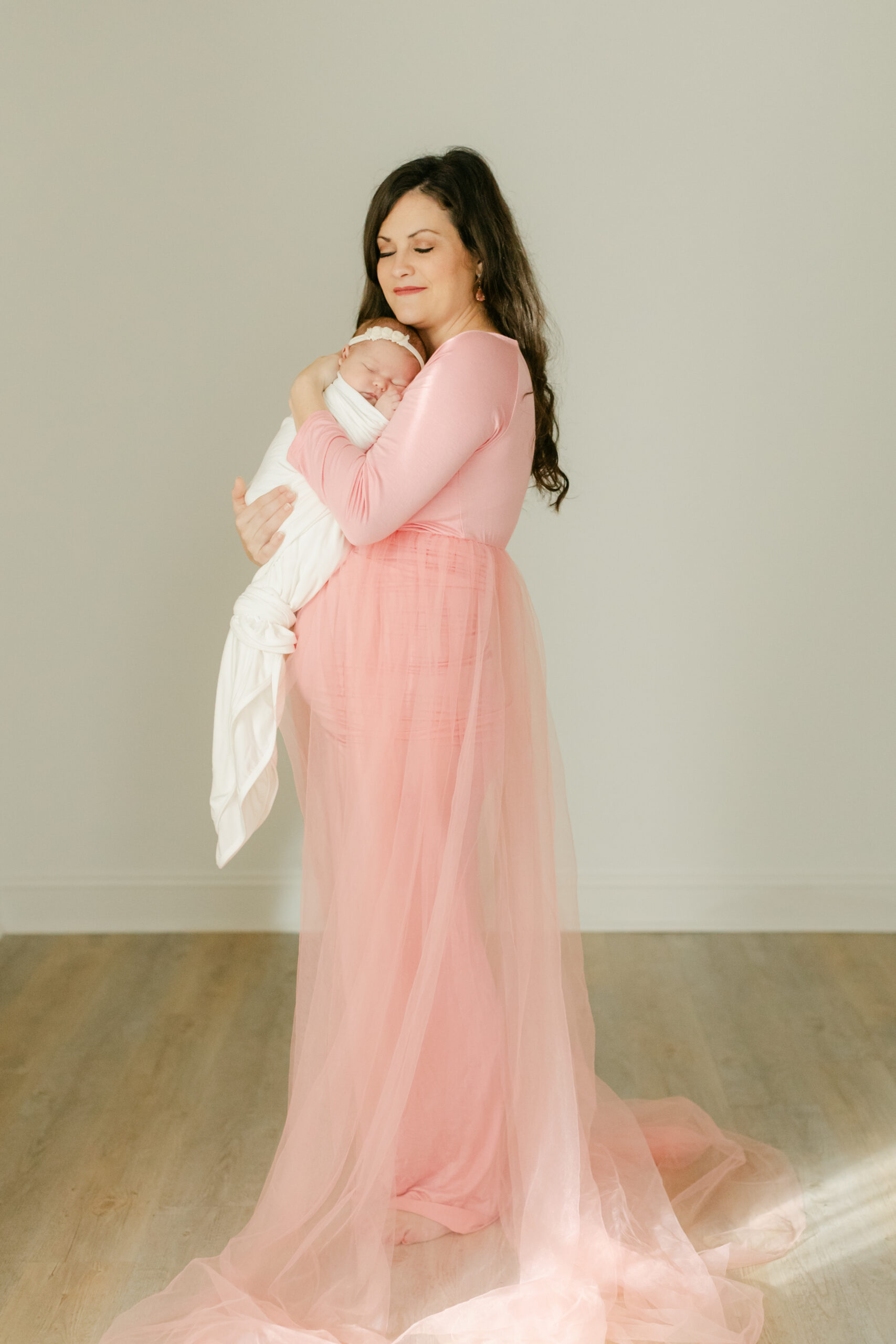 mama in pink dress holding sleepy newborn baby girl