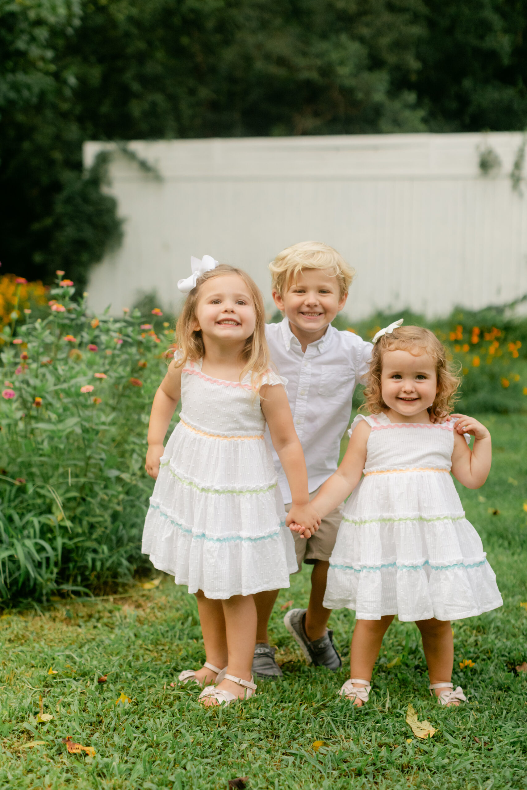 three young siblings in flower garden during motherhood minis photo session in nashville