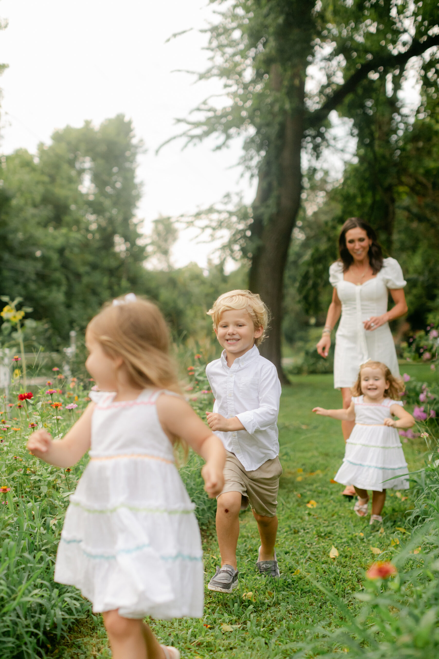 mama and her three young kids running in flower garden. motherhood minis photo session in nashville