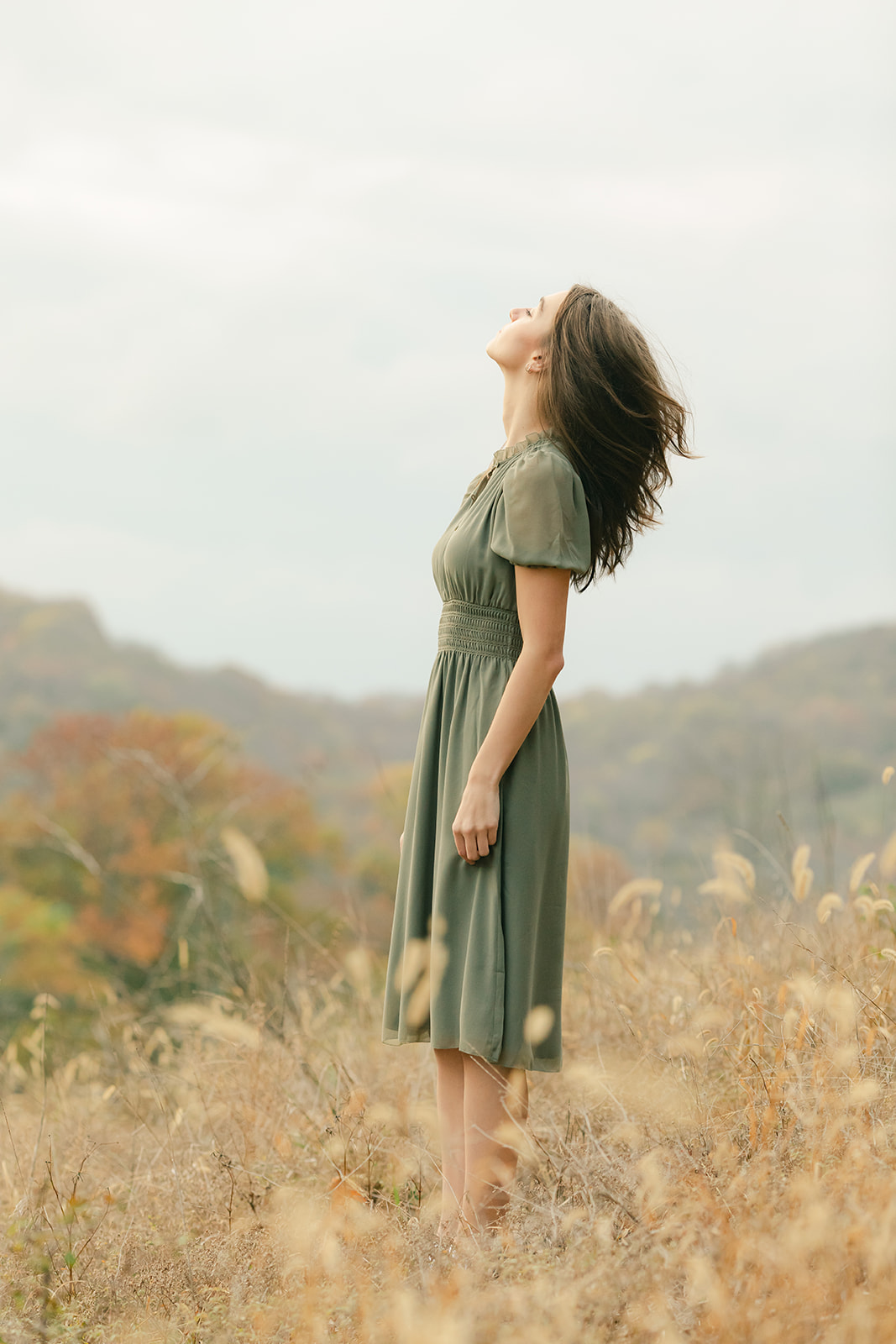 teenage girl during fall senior photos in open field.