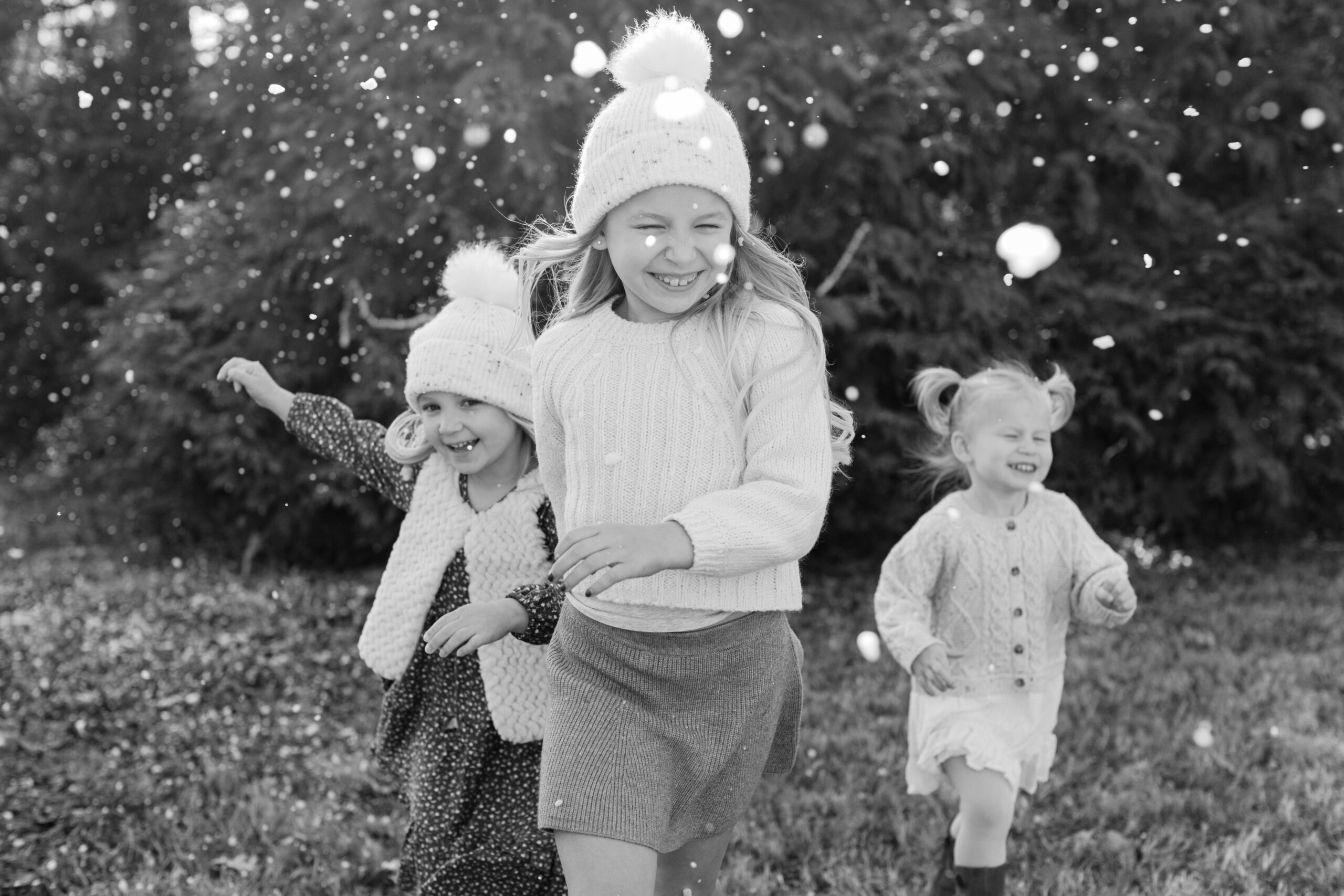 3 little sisters playing in snow.  christmas themed family photos in tennessee with fake snow