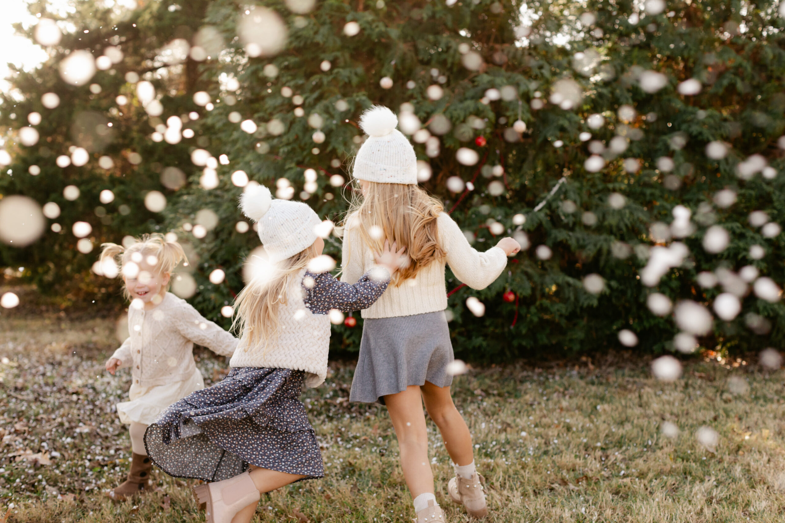 3 little. sisters playing in snow. christmas themed family photos in tennessee with fake snow