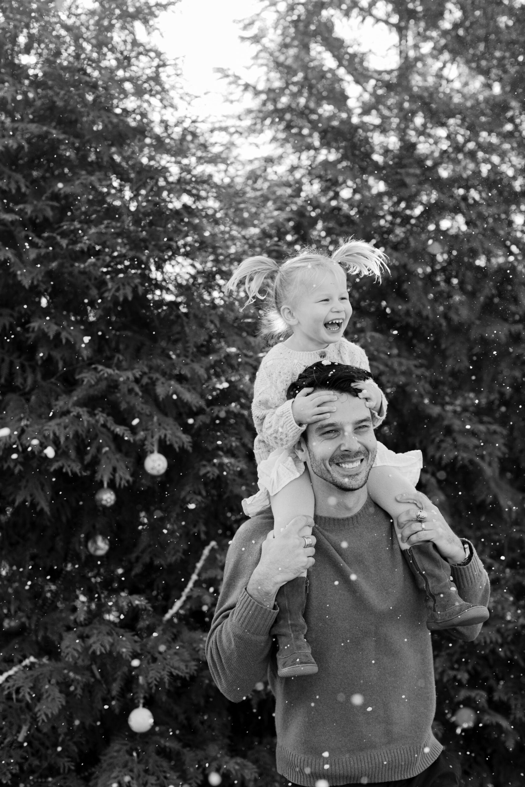 dad with young daughter on shoulders. christmas themed family photos in tennessee with fake snow