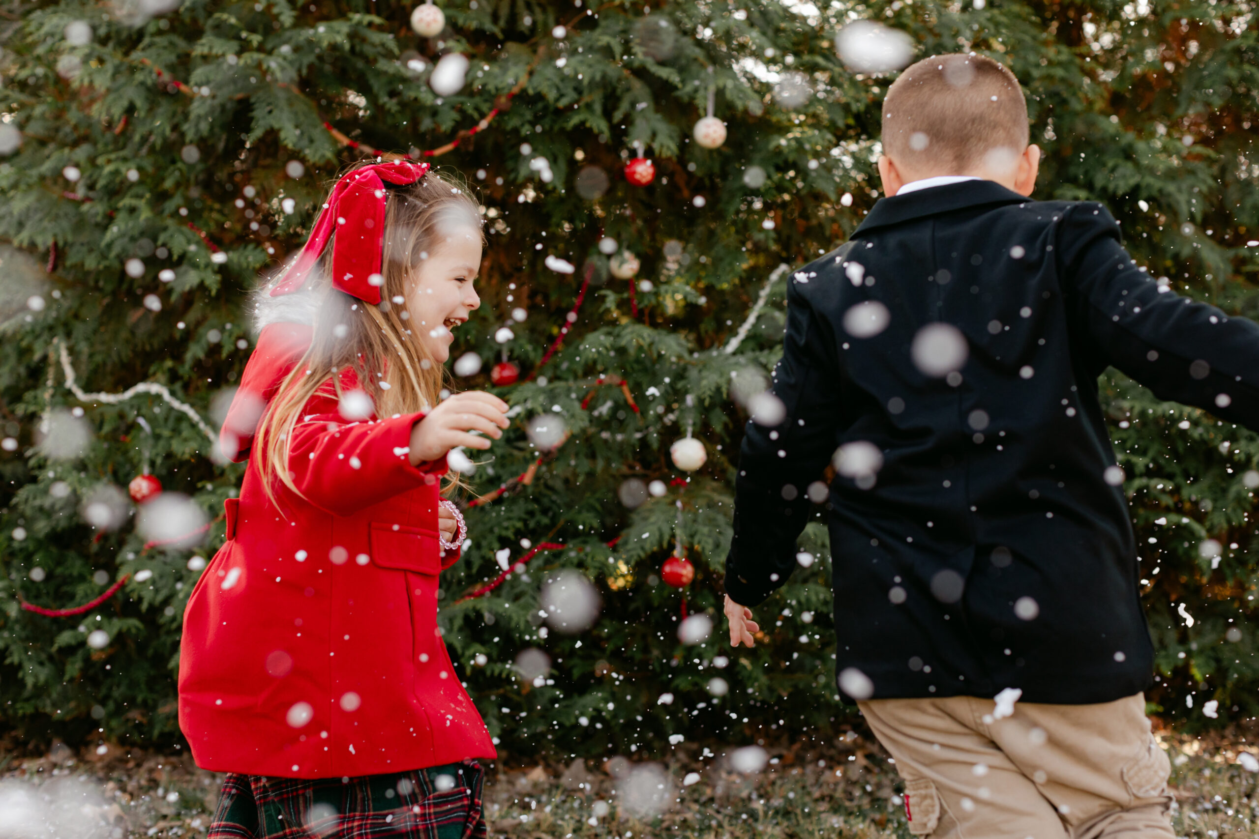 siblings playing with snow.  christmas themed family photos in tennessee with fake snow