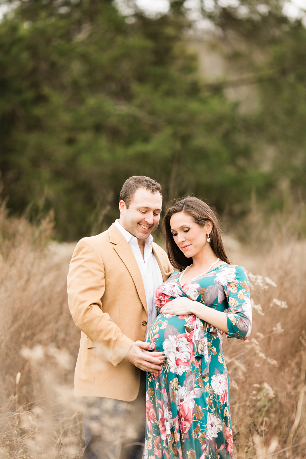 couple posing during outdoor maternity session in grassy field