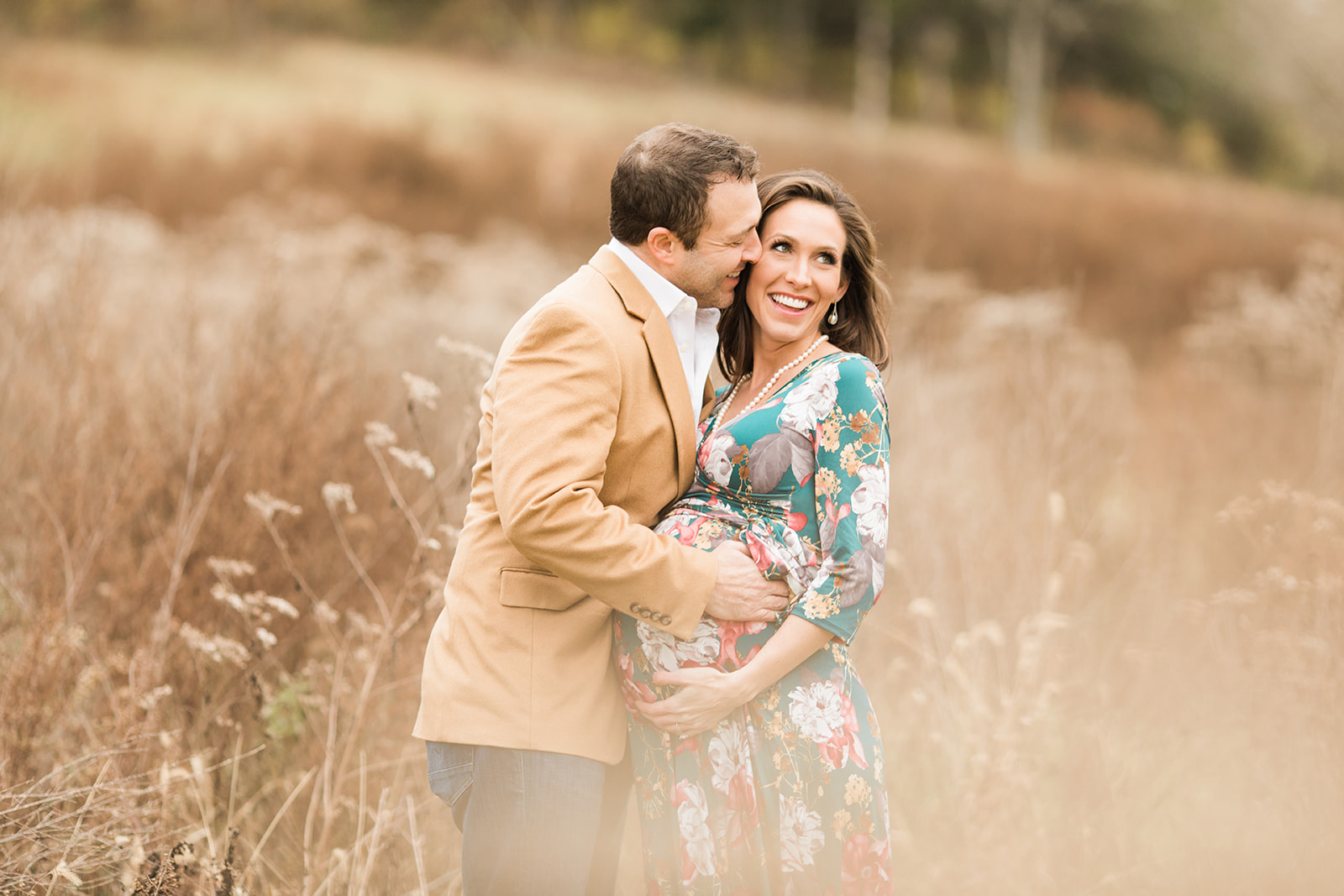 couple posing during outdoor maternity session in grassy field