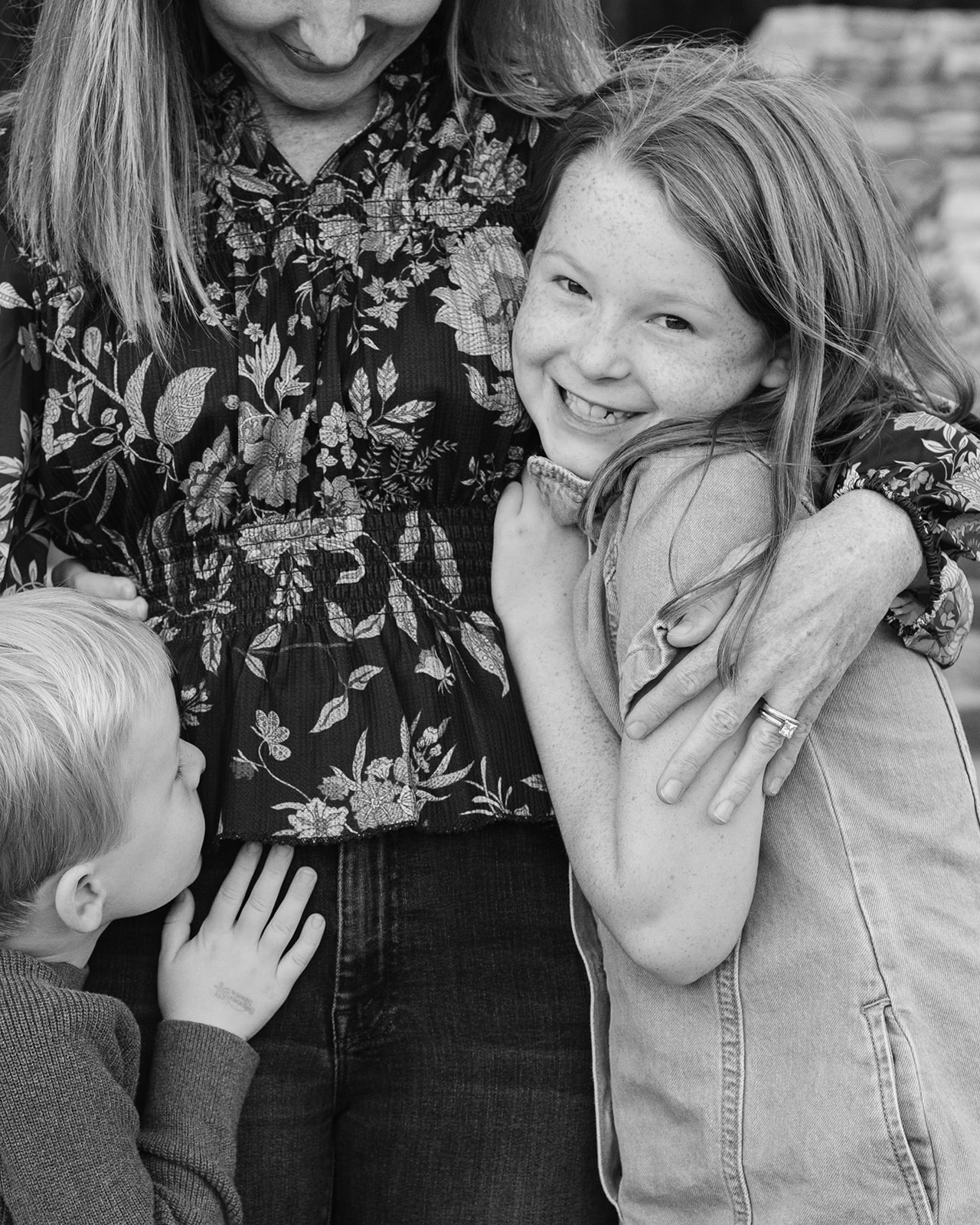 a mom hugs both her children tightly as they get cozy for casual family photos.