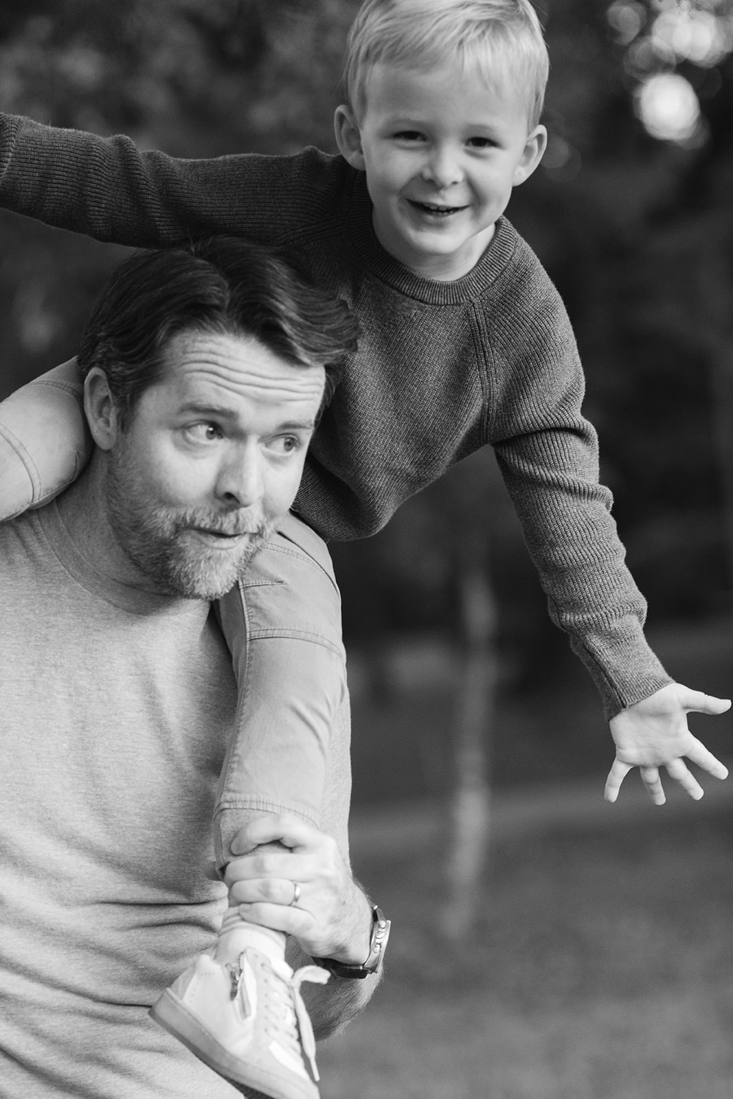 a dad gives his son a piggy back ride during family photos