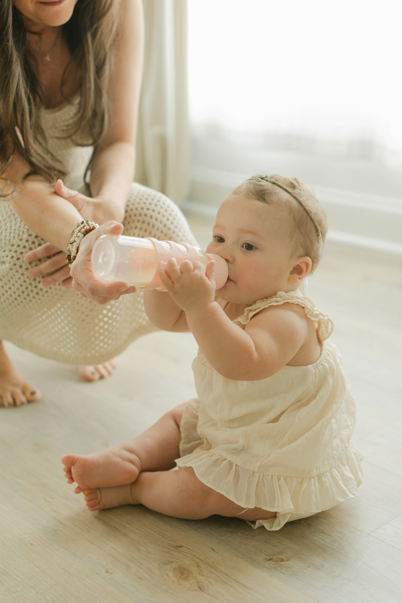 baby girl drinking milk. 10 month old baby milestone session