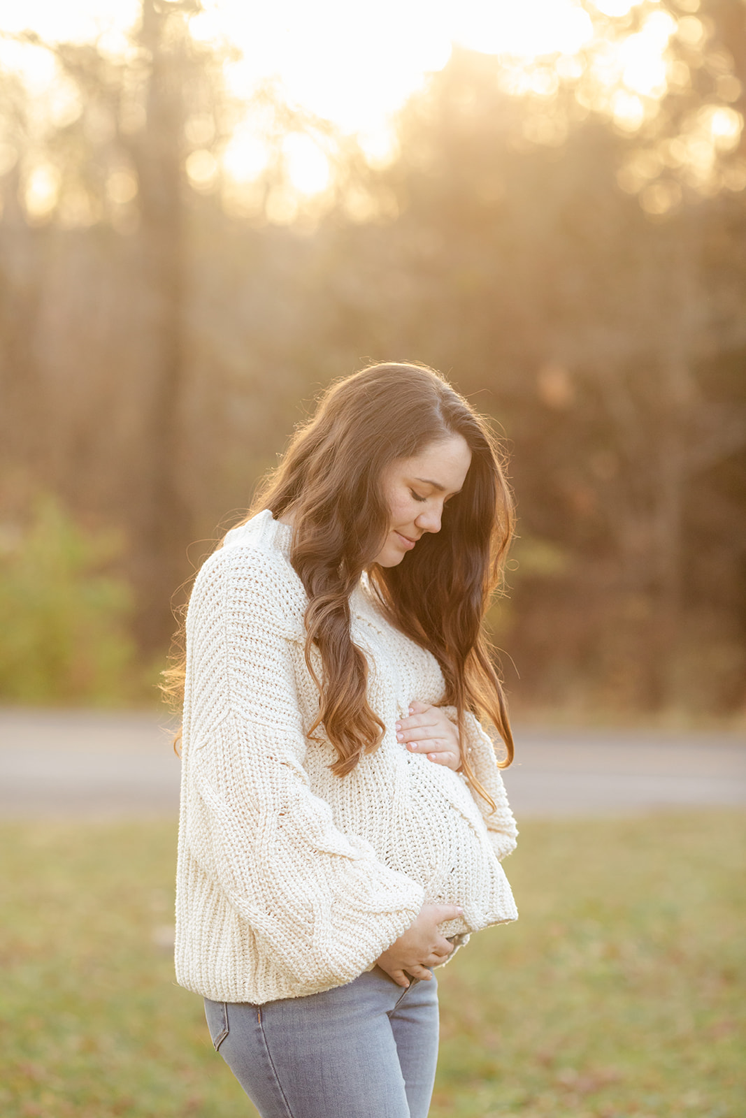 An expectant mother poses for maternity photos in golden hour light of sunset outside a photographer's studio in Franklin, Tn. 