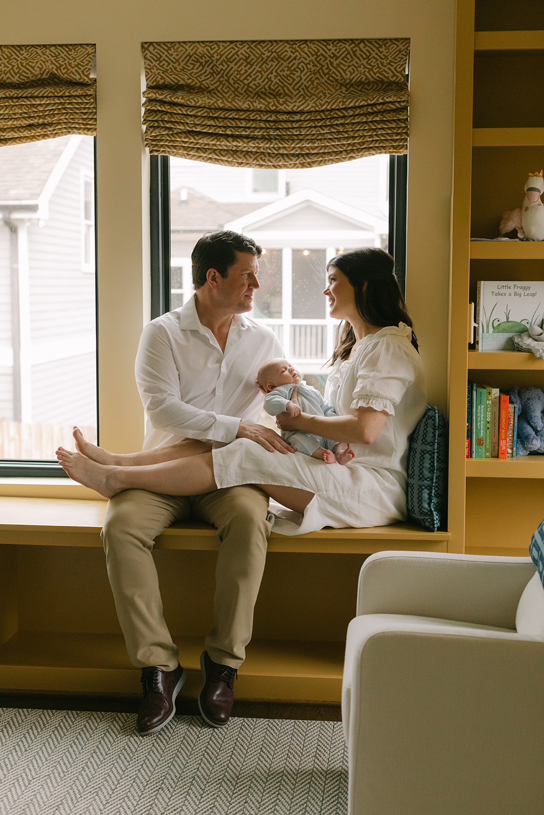 parents on window seal with newborn son