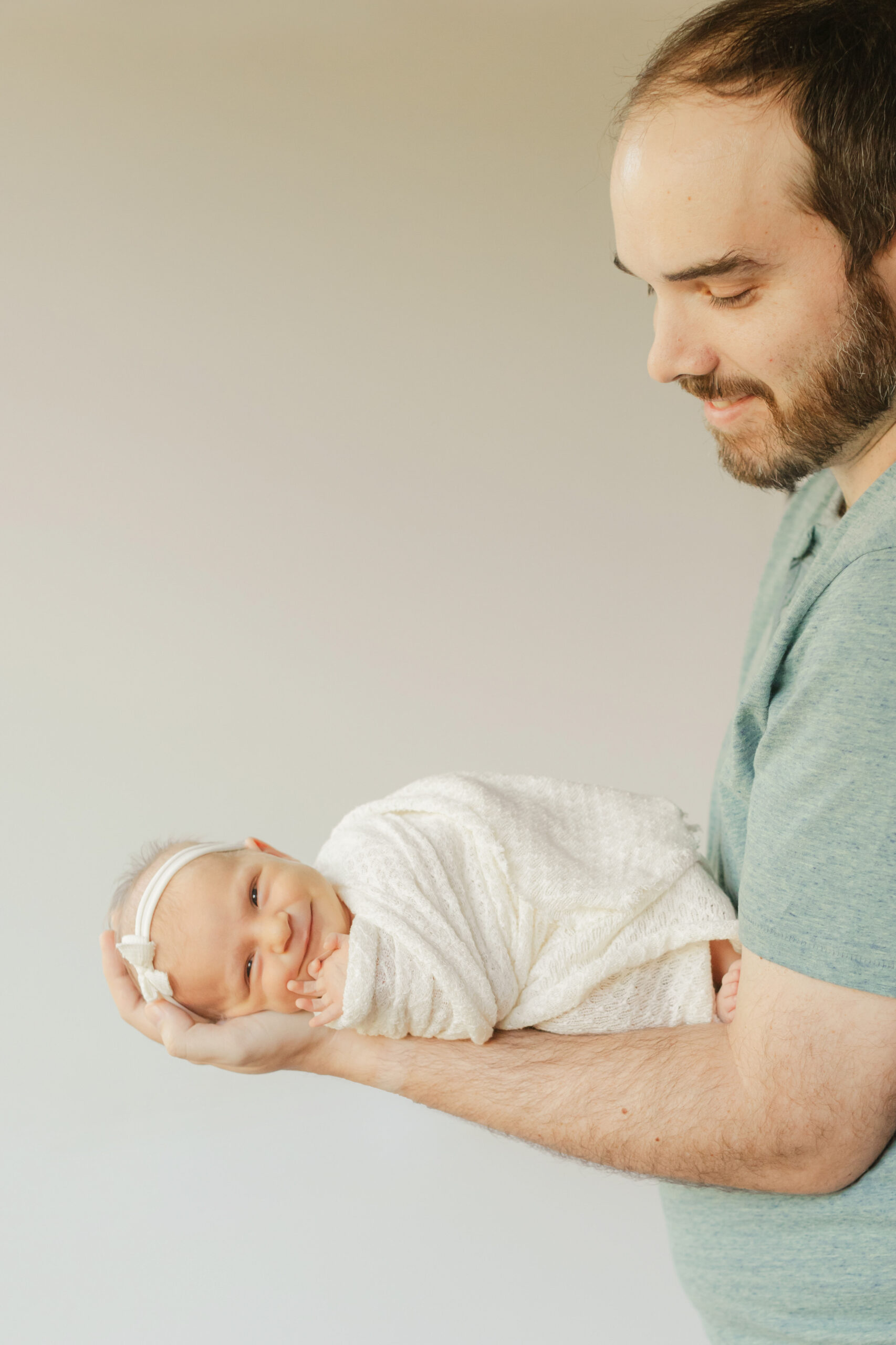 dad holding newborn daughter in arm
