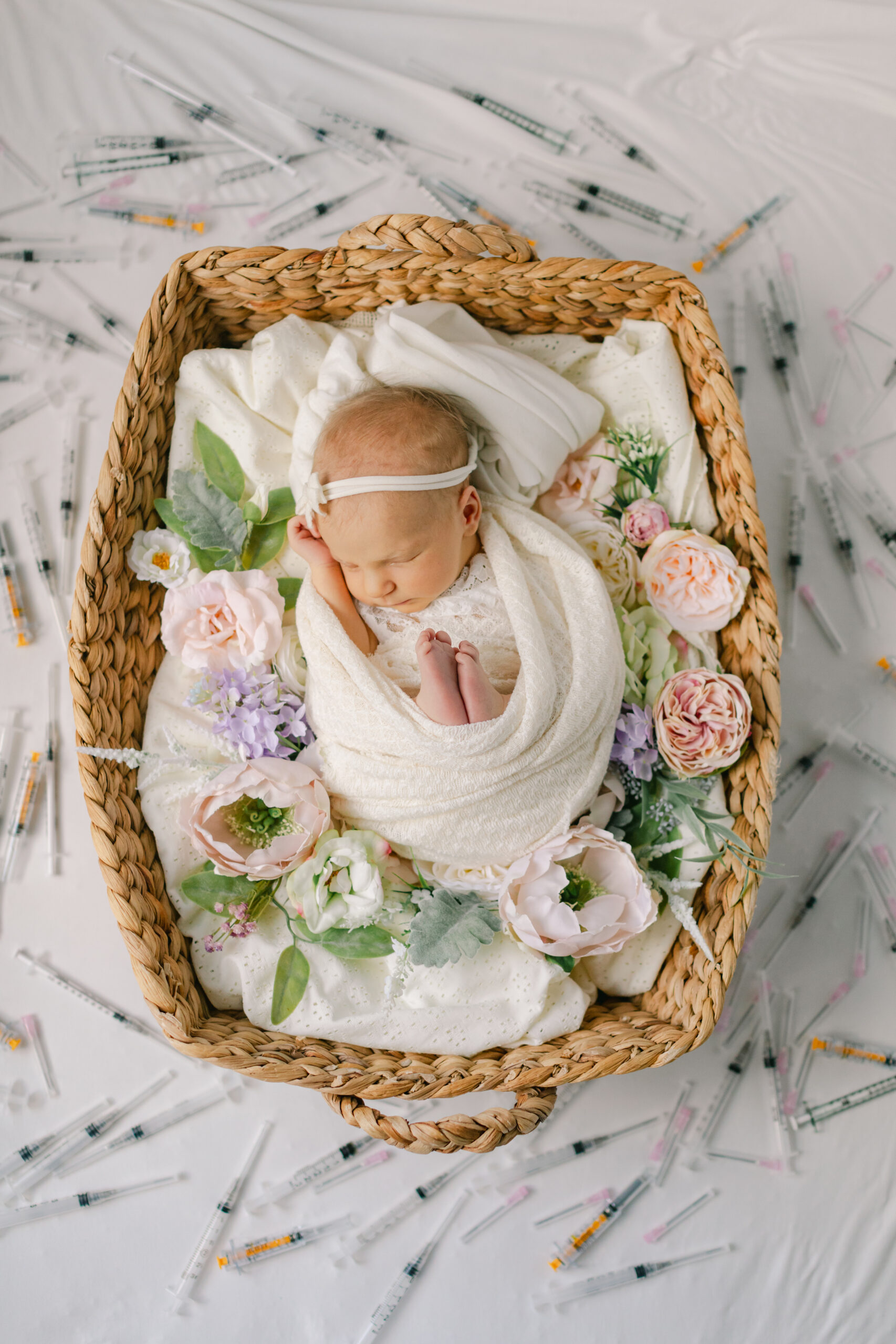 sleepy newborn baby girl in basket with flowers. IVF baby