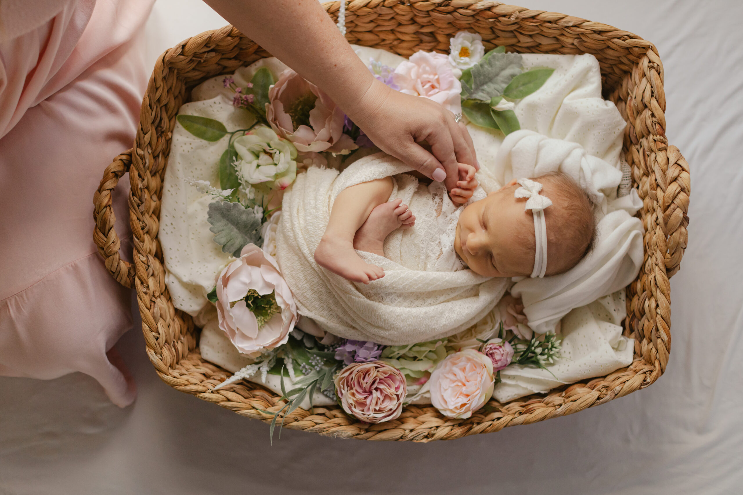 sleepy newborn baby girl in basket with flowers