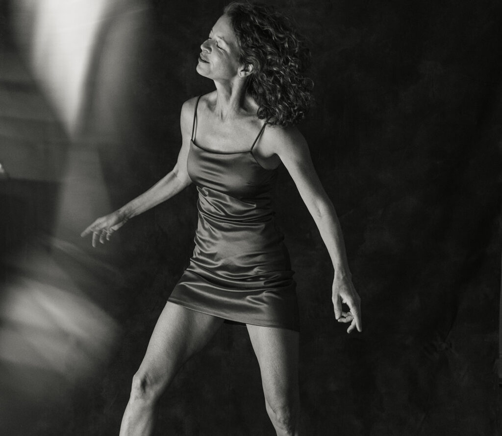 black and white photo of a woman in her 50s dancing in a mini dress