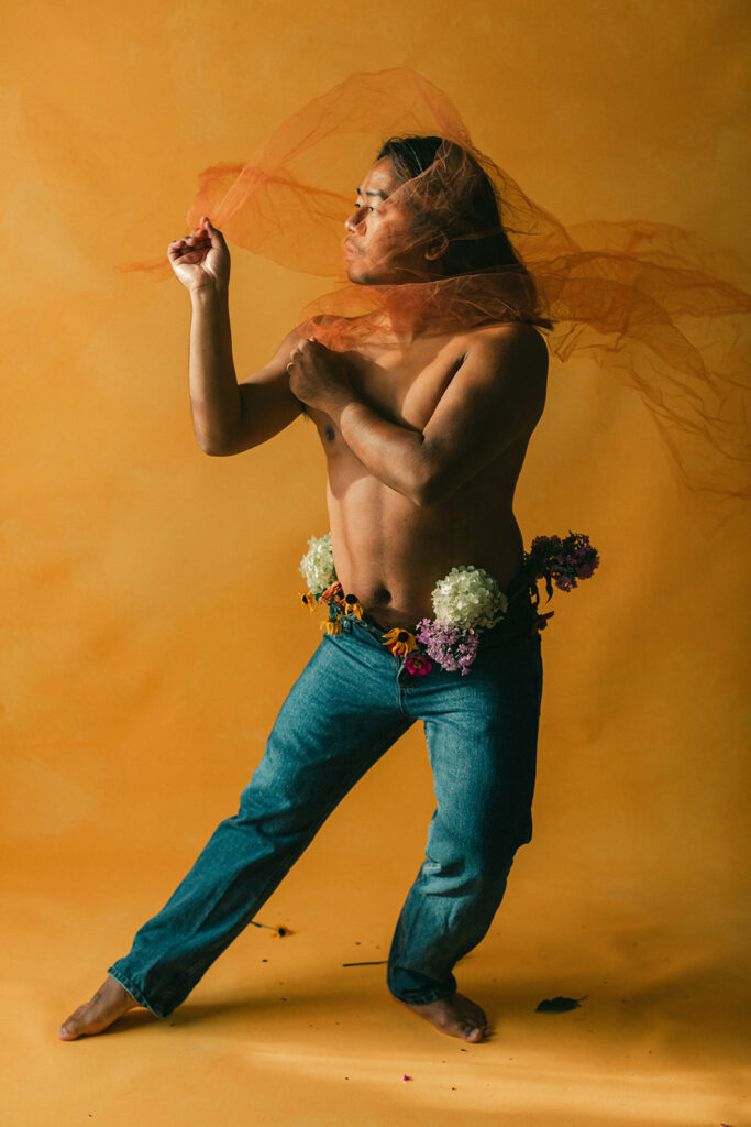 gay man poses topless with jeans & flowers & tule for Nashville, Tn body empowerment + boudoir photographer