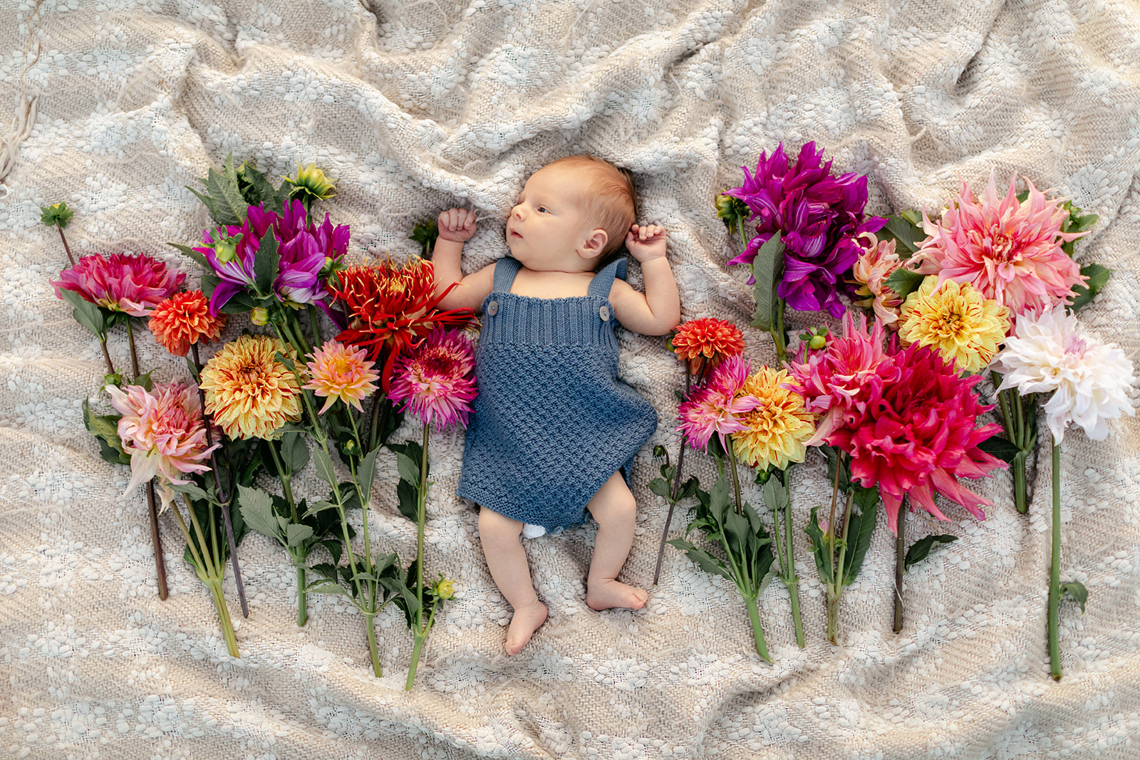 newborn baby boy on blanket surrounded by flowers